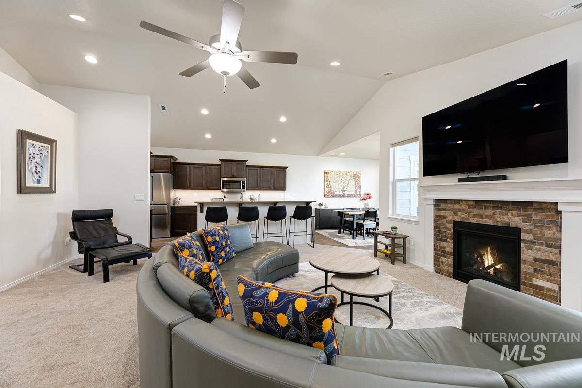 Living room with light colored carpet, recessed lighting, vaulted ceiling, a ceiling fan, and a fireplace