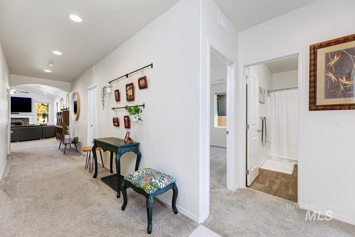Hallway featuring light colored carpet, arched walkways, and recessed lighting