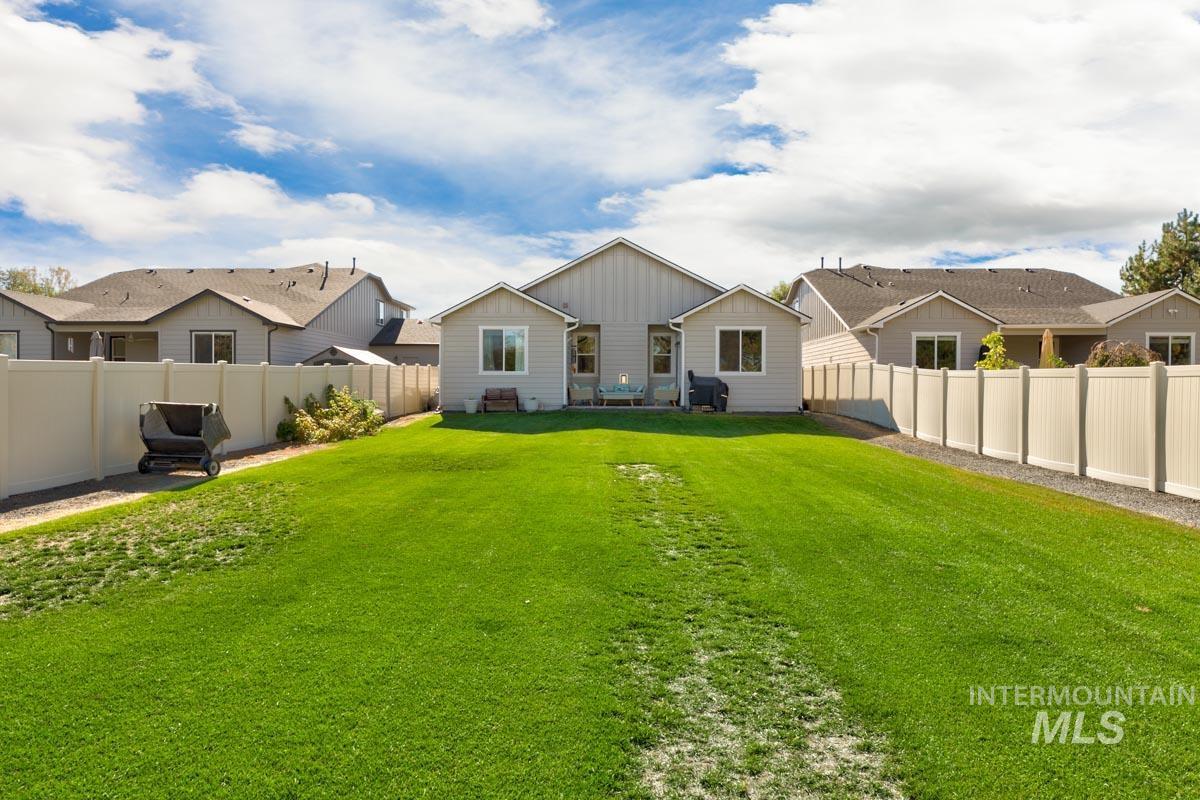 Rear view of property featuring board and batten siding, a fenced backyard, and a residential view