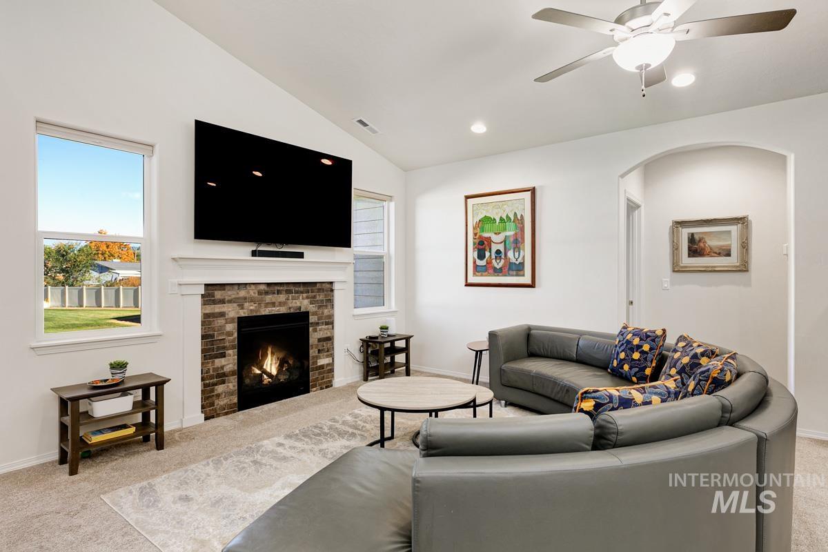 Living area featuring carpet, lofted ceiling, a fireplace, arched walkways, and recessed lighting