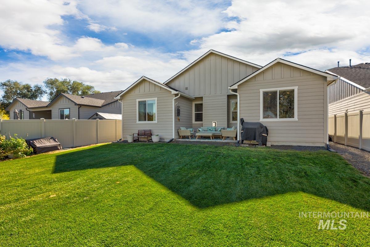 Back of property with a fenced backyard, outdoor lounge area, board and batten siding, and a patio area