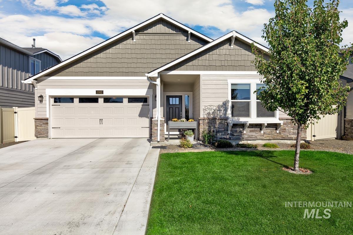 Craftsman-style home featuring stone siding, a front yard, driveway, and an attached garage