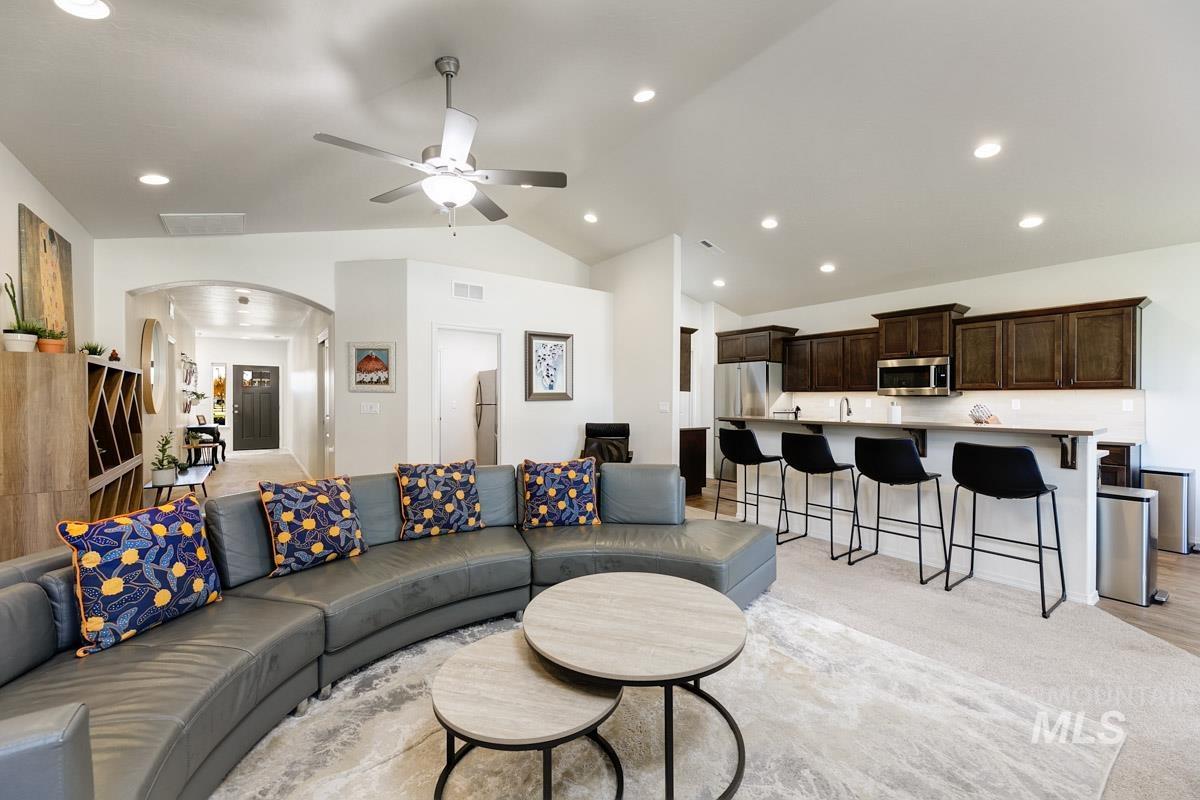 Living room featuring vaulted ceiling, arched walkways, a ceiling fan, recessed lighting, and light carpet