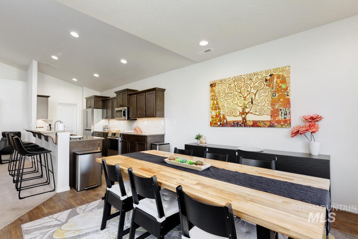 Dining space featuring light wood-style floors, lofted ceiling, and recessed lighting