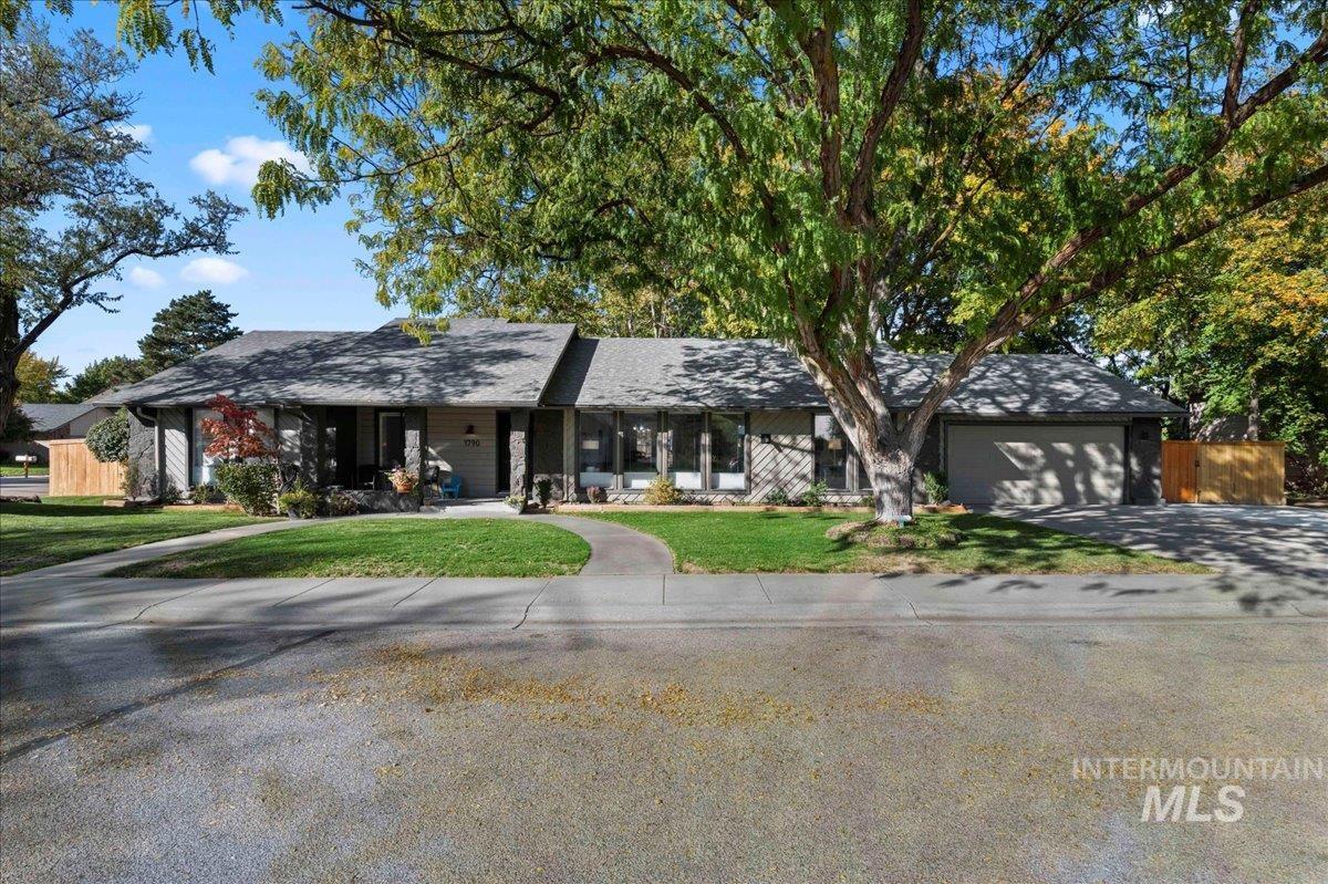 Single story home featuring concrete driveway, an attached garage, and covered porch
