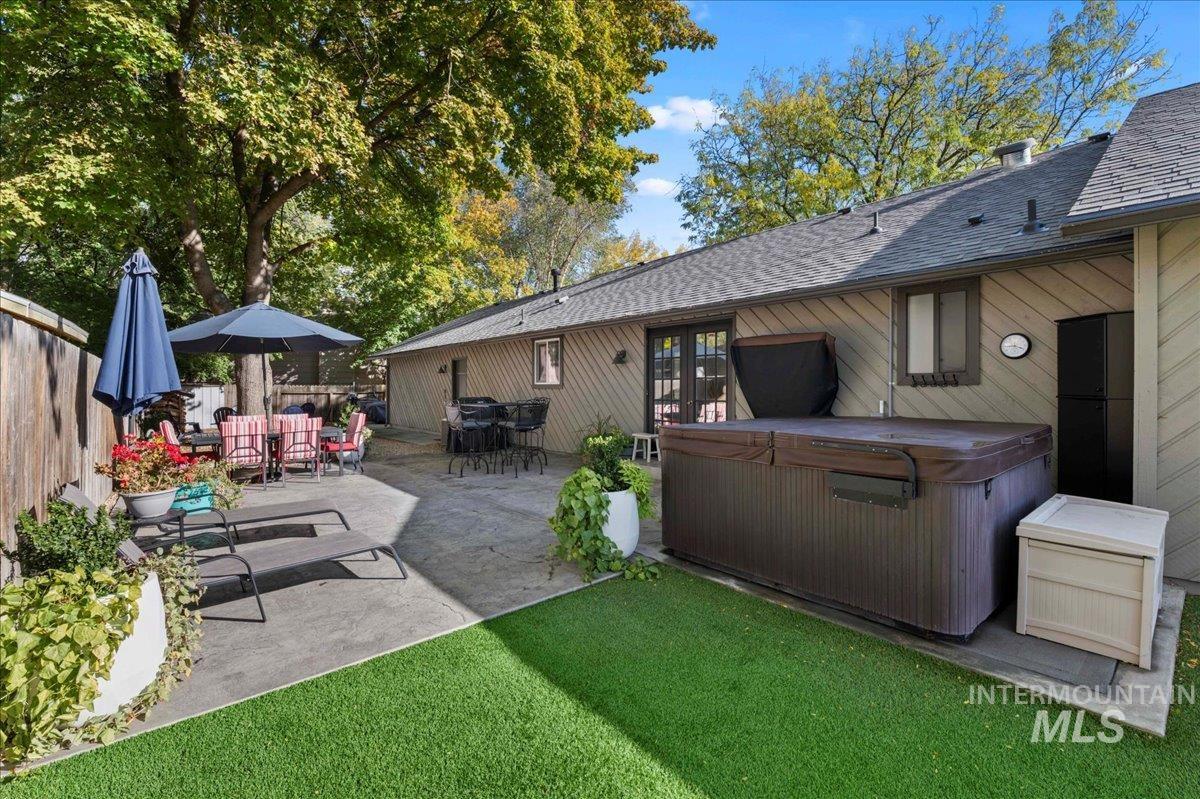 Rear view of property featuring roof with shingles, a hot tub, a patio, and outdoor dining space