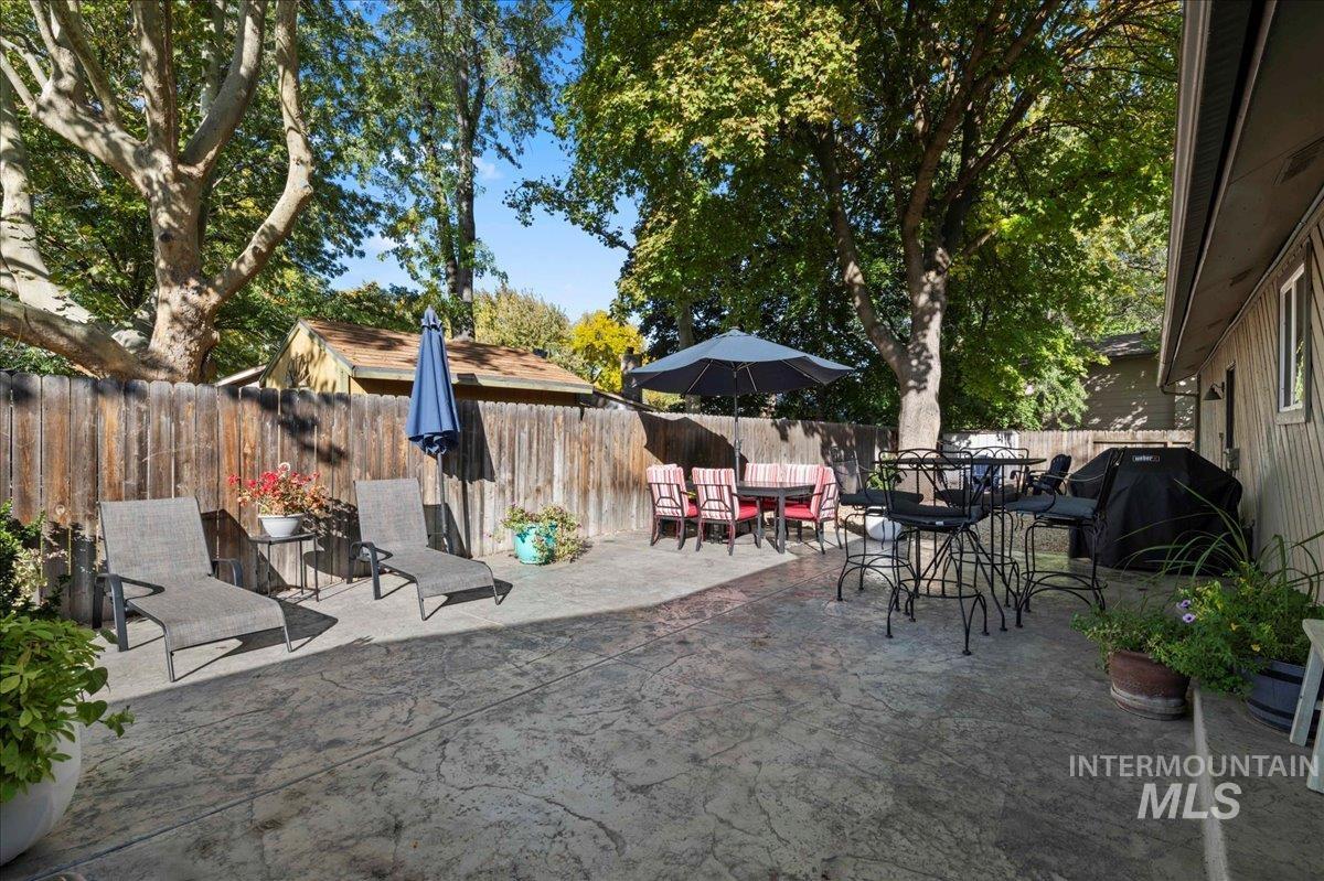 Fenced backyard featuring a patio, outdoor dining space, and a grill