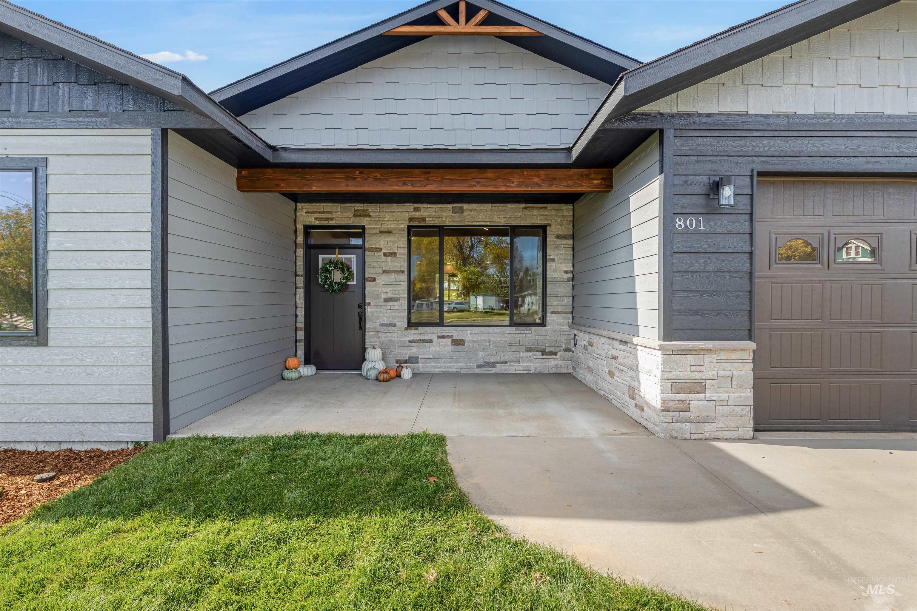 Property entrance featuring a garage, stone siding, and a lawn