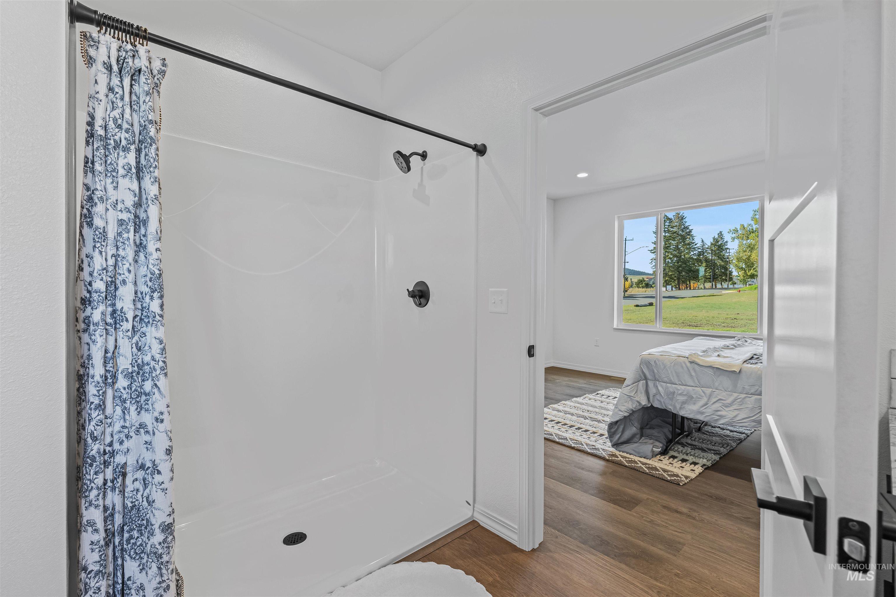 Ensuite bathroom featuring a stall shower, dark wood-type flooring, and recessed lighting