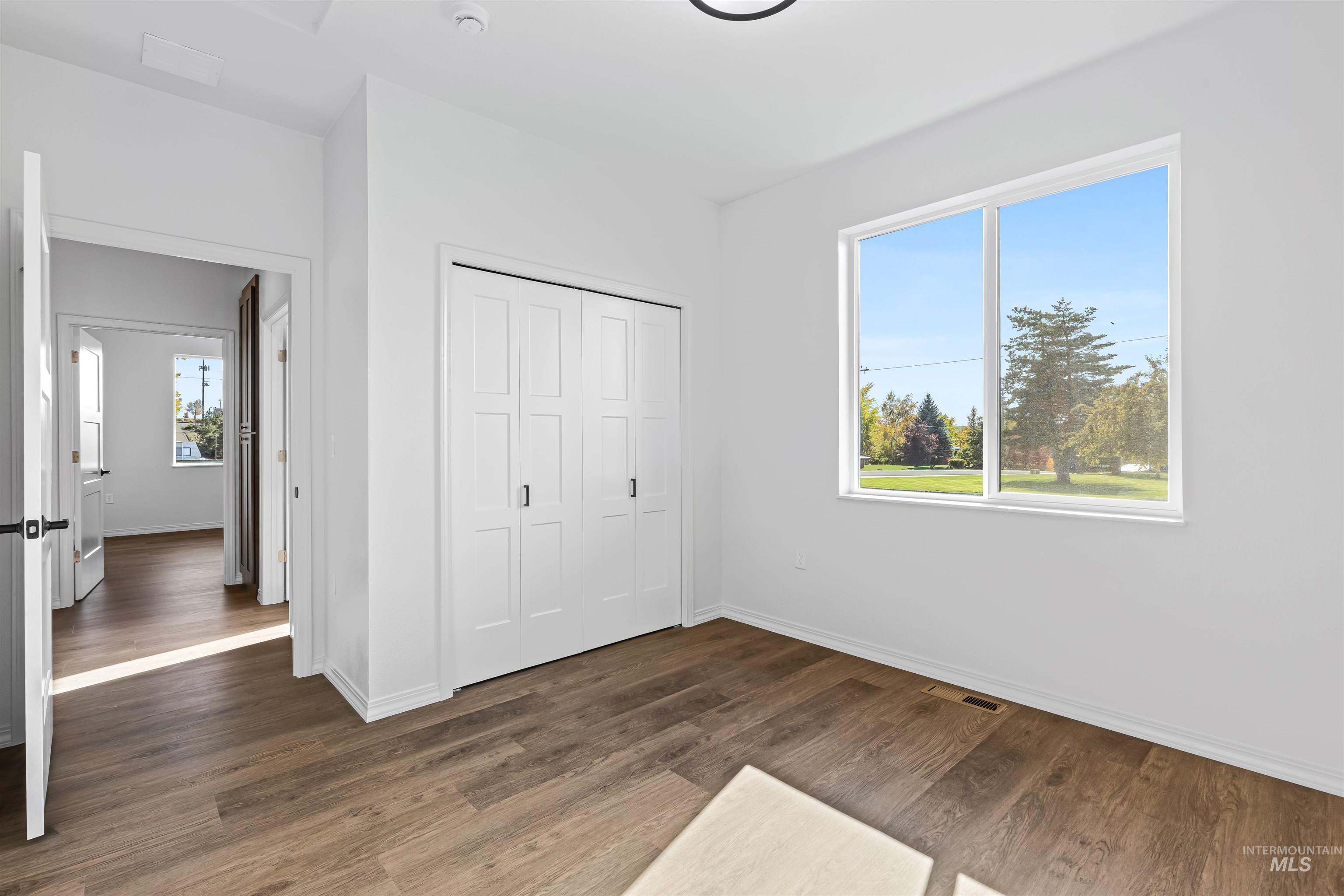 Unfurnished bedroom featuring dark wood-style flooring and a closet