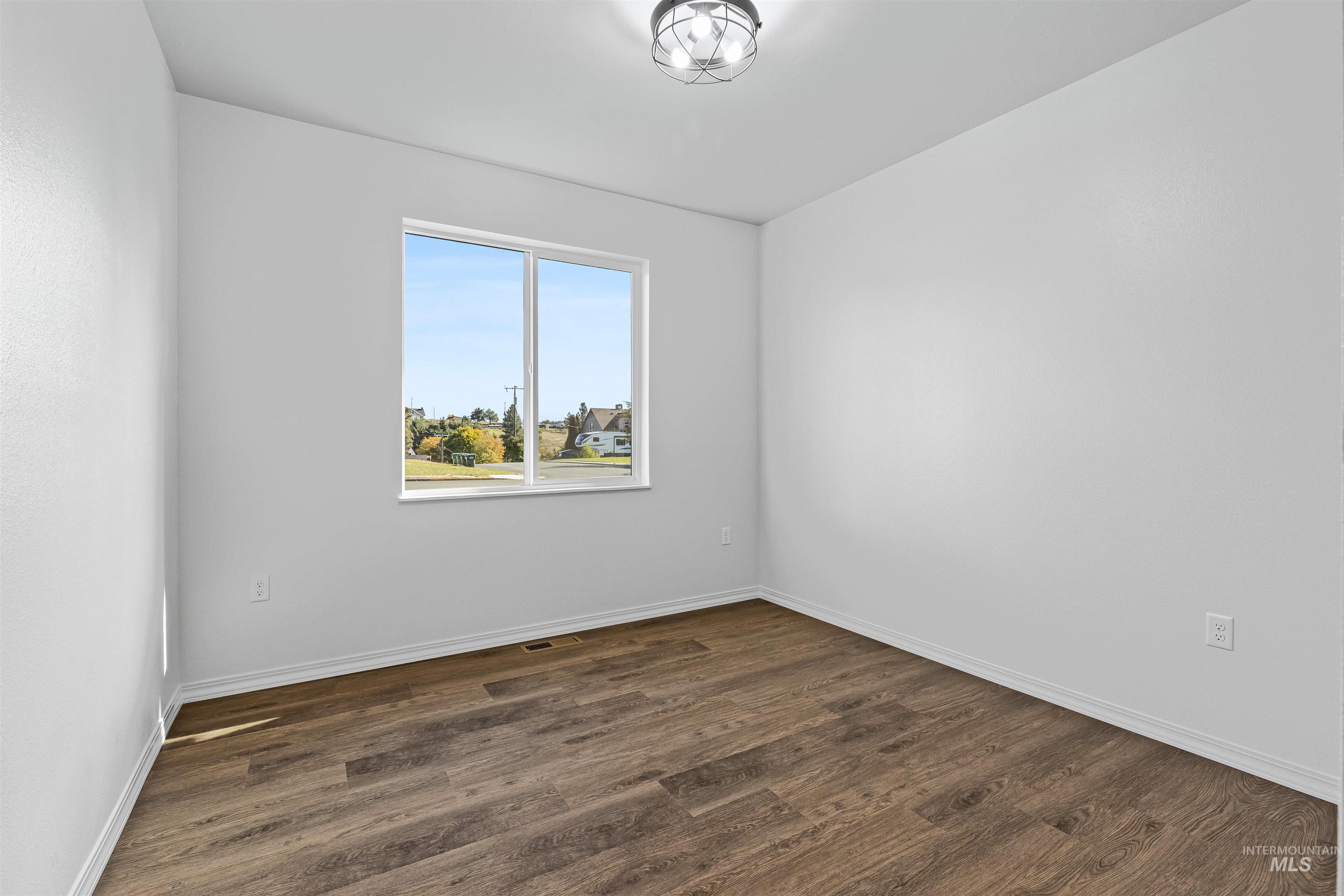 Spare room featuring dark wood finished floors and baseboards