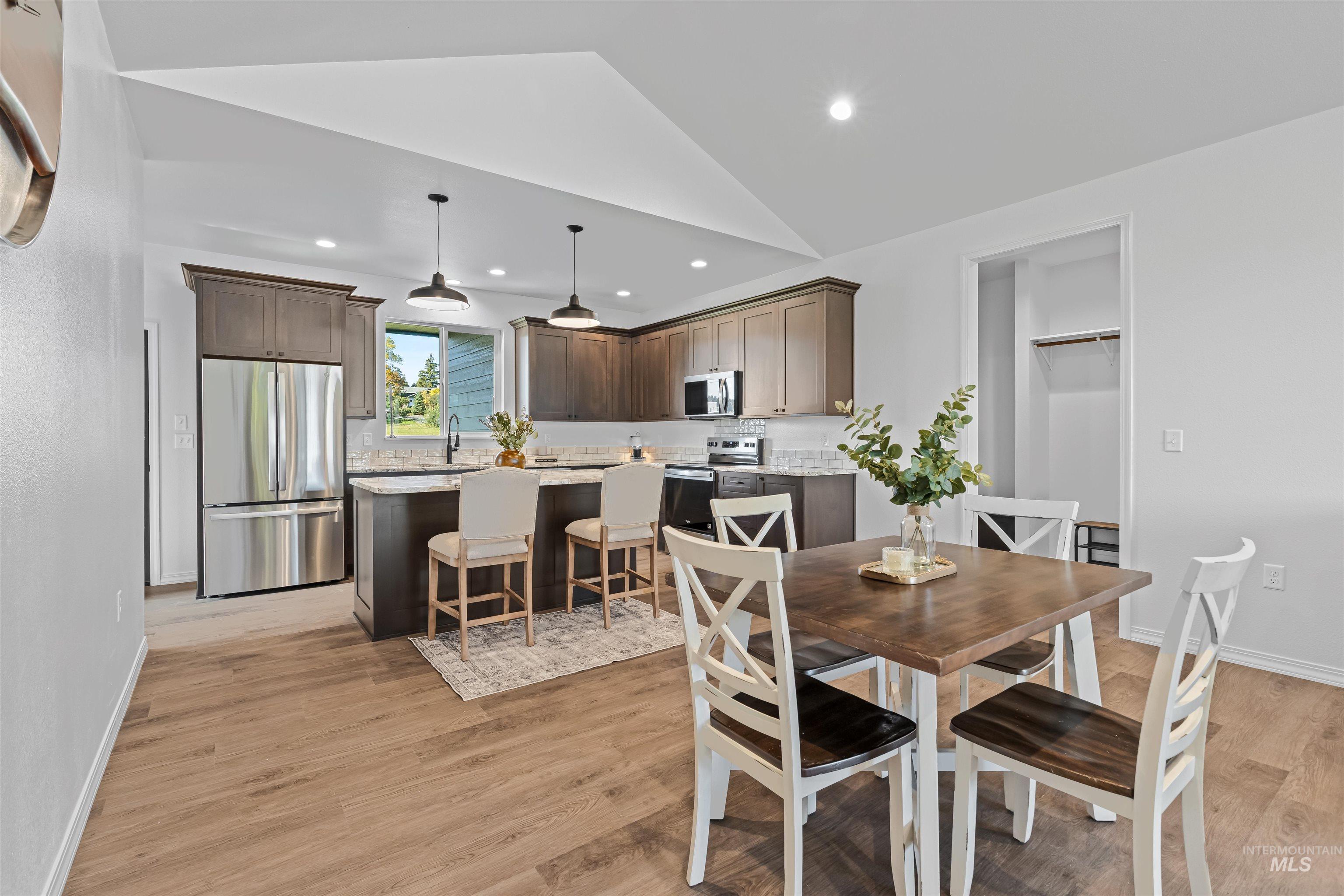 Dining space with lofted ceiling, light wood-type flooring, and recessed lighting