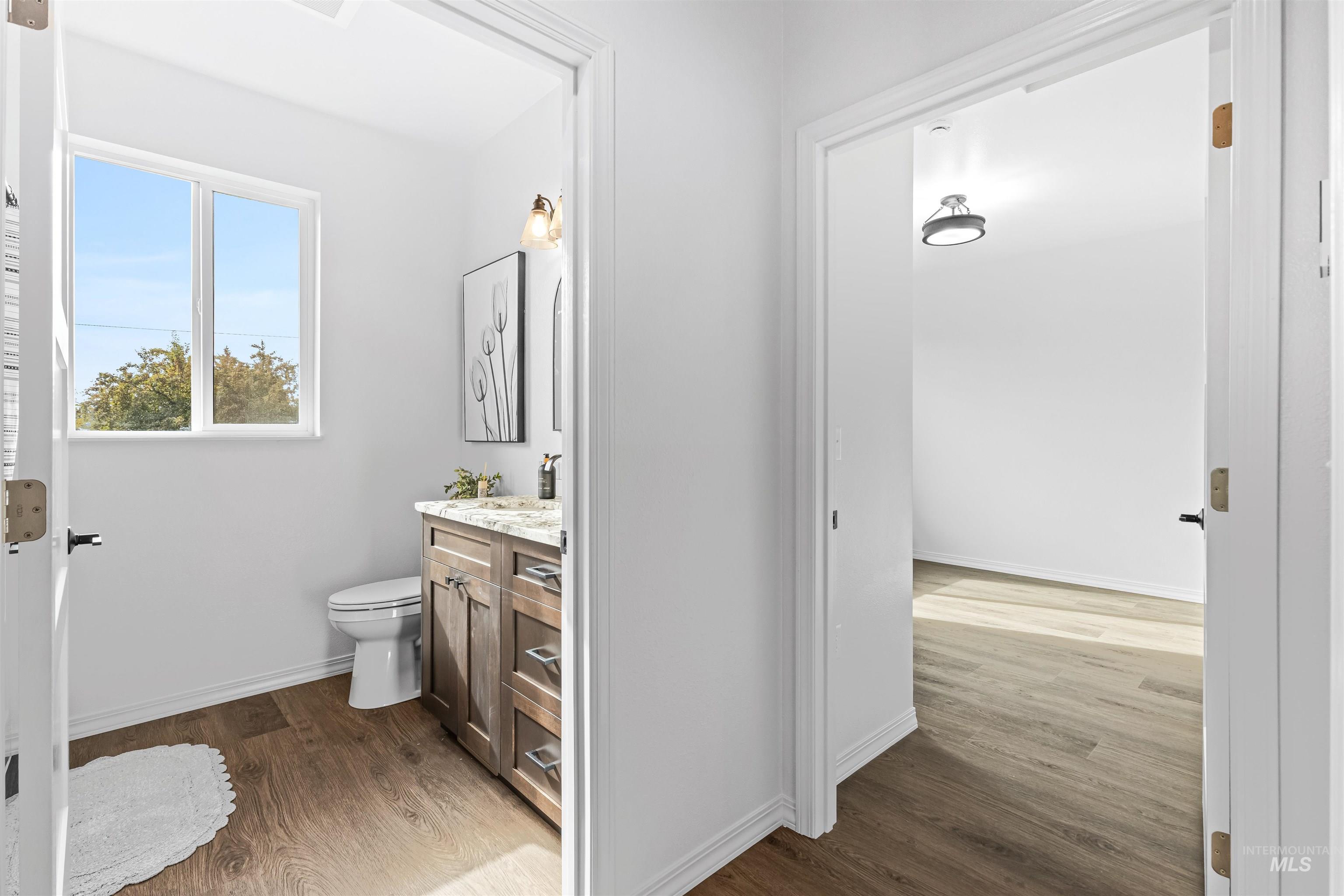 Half bathroom with vanity and dark wood-type flooring