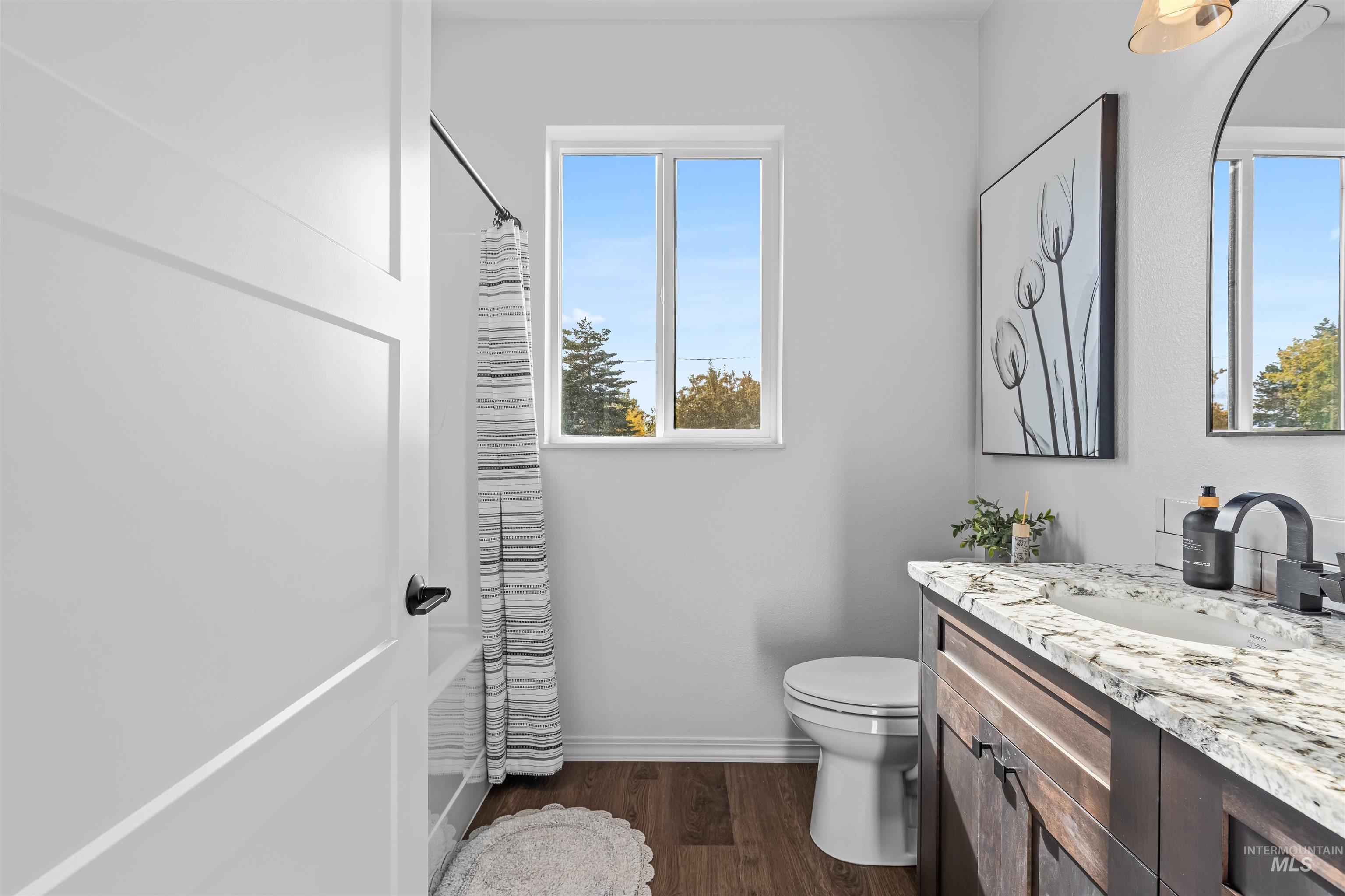 Bathroom with dark wood finished floors, vanity, and shower / bath combo with shower curtain
