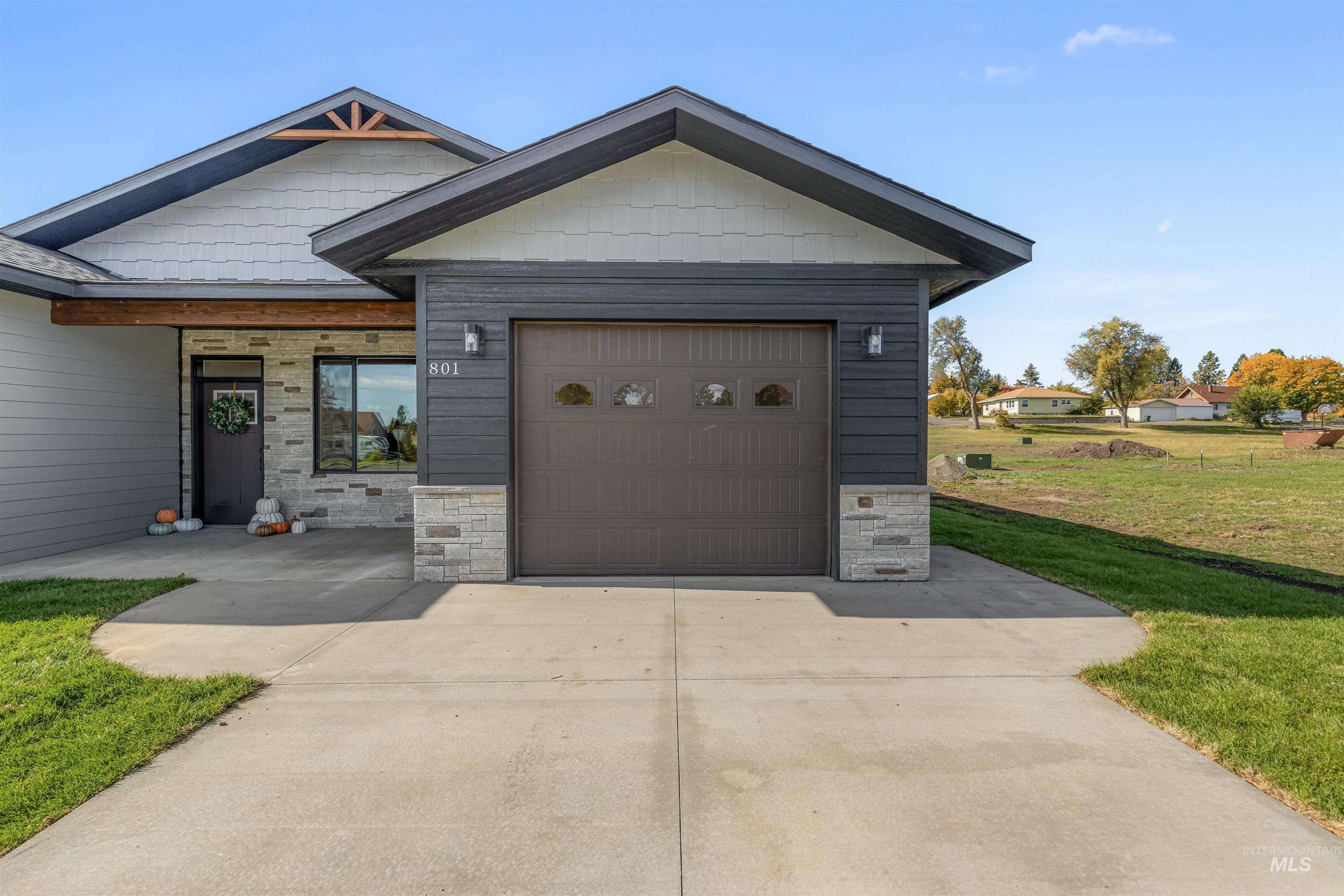 View of front of house featuring stone siding, a front lawn, driveway, and an attached garage