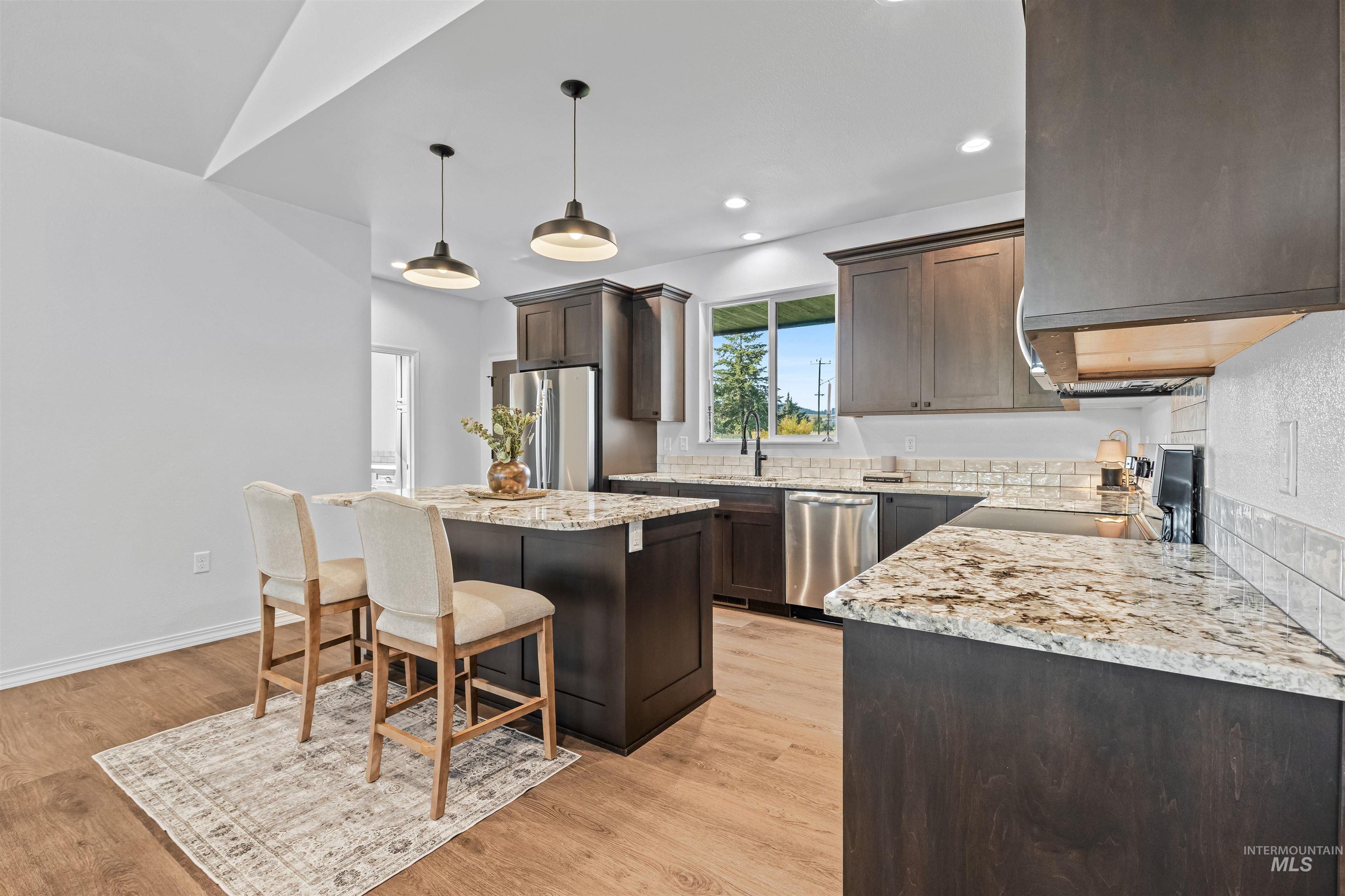 Kitchen featuring a kitchen island, dark brown cabinets, hanging light fixtures, a kitchen bar, and recessed lighting