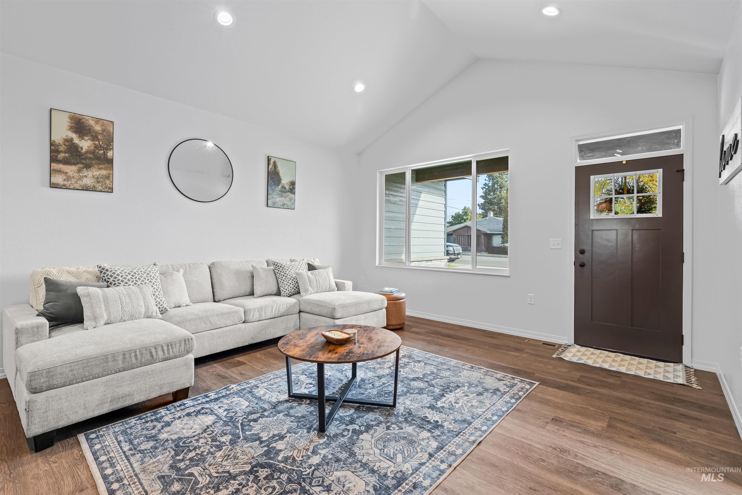 Living area with dark wood-style flooring, recessed lighting, and high vaulted ceiling