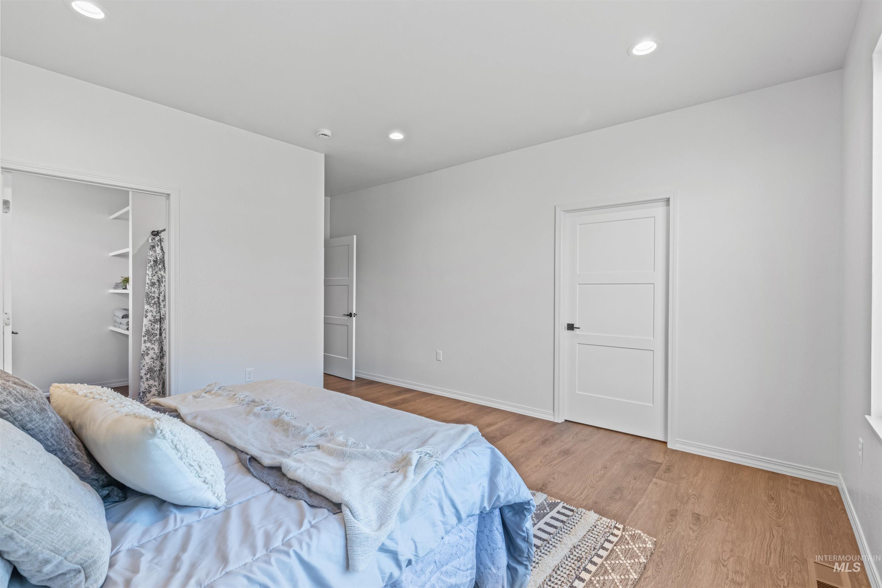 Bedroom with wood finished floors, recessed lighting, and a closet