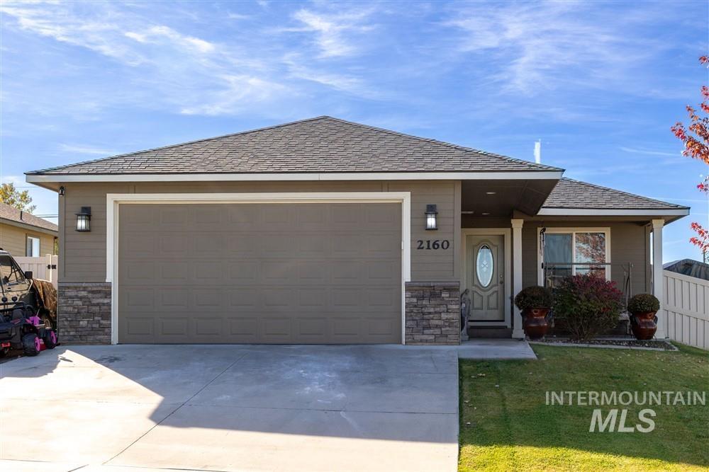 Single story home with stone siding, concrete driveway, a shingled roof, and a garage