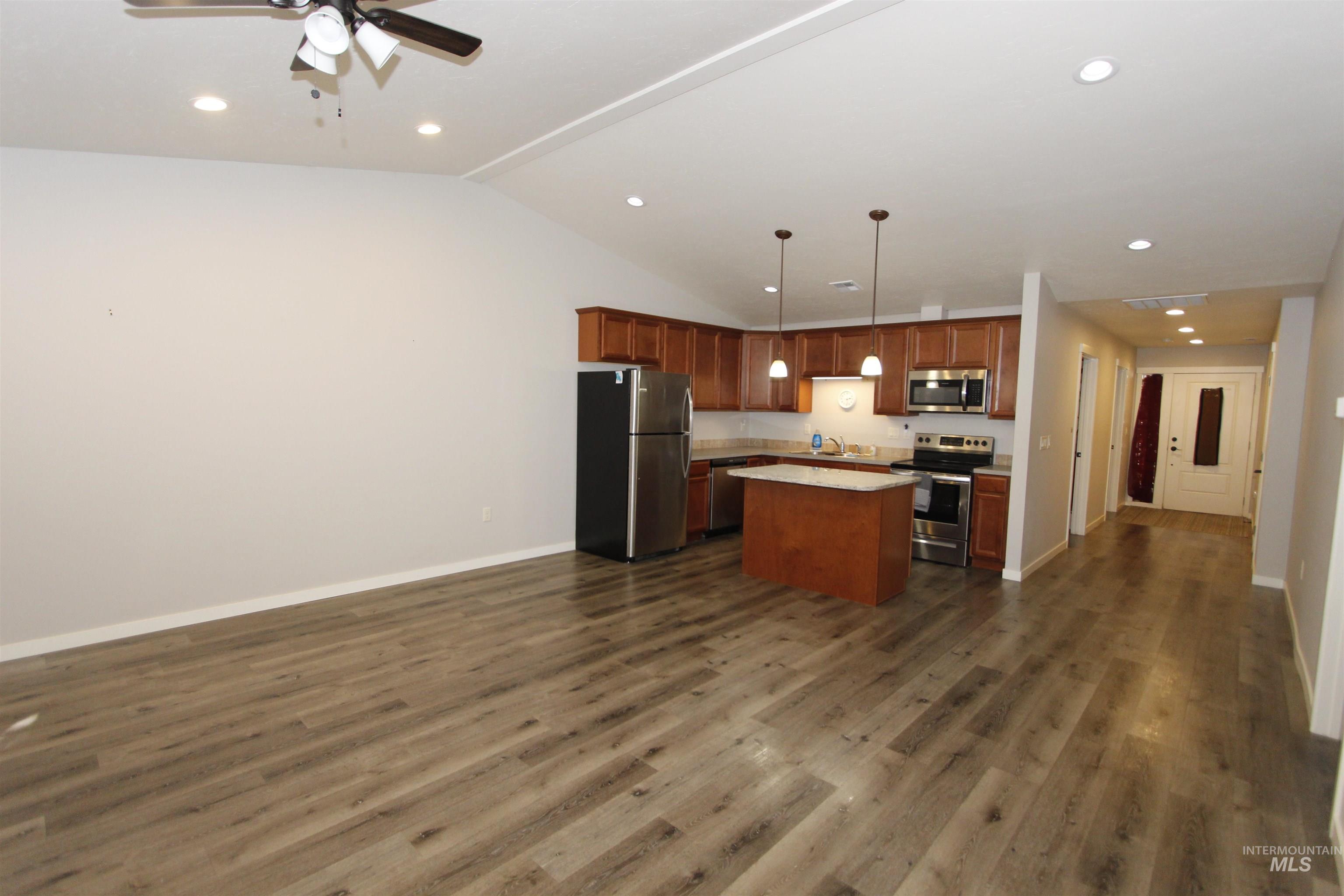 Kitchen featuring open floor plan, stainless steel appliances, a center island, light countertops, and pendant lighting