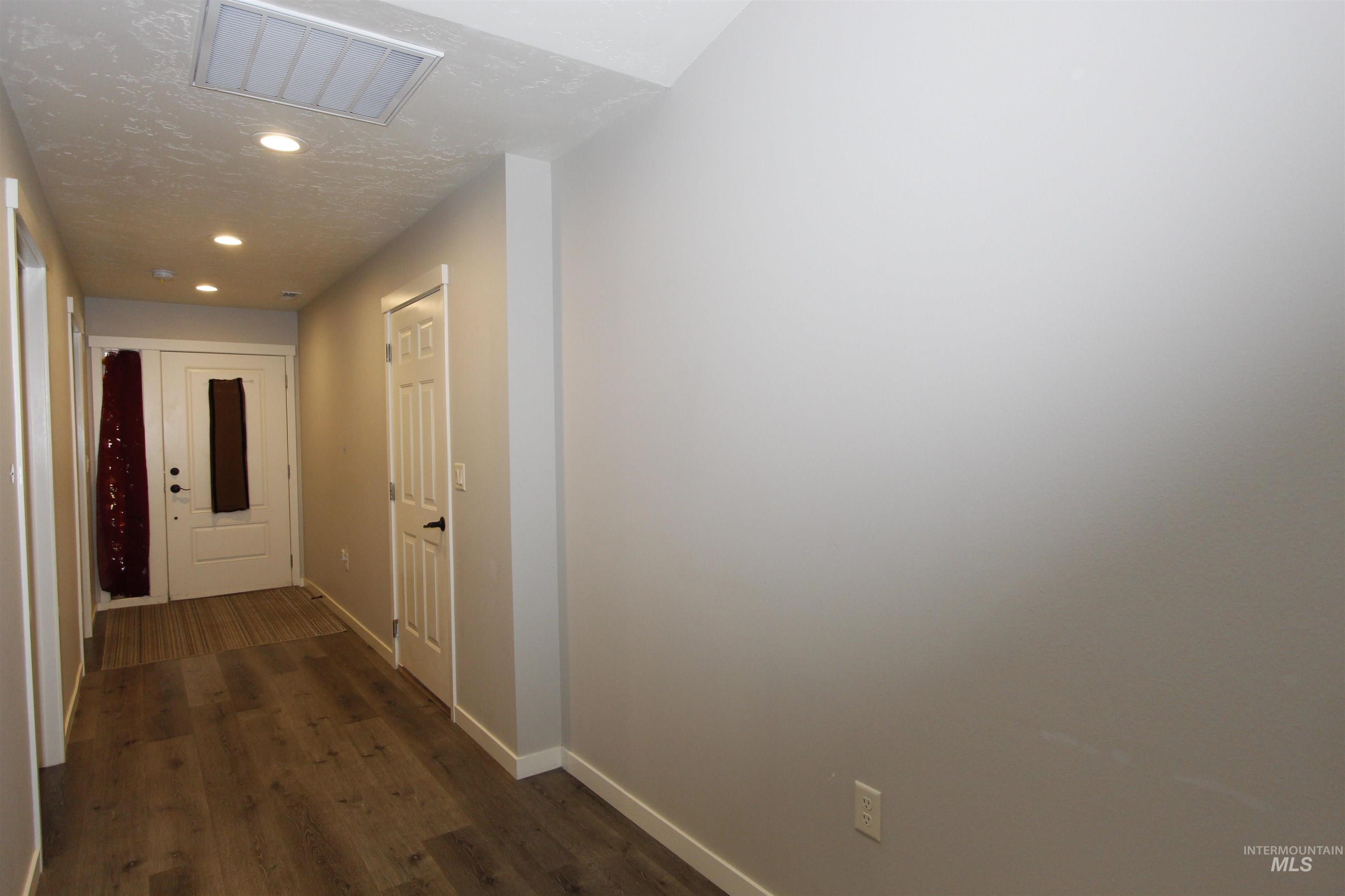 Hallway featuring a textured ceiling, dark wood finished floors, and recessed lighting