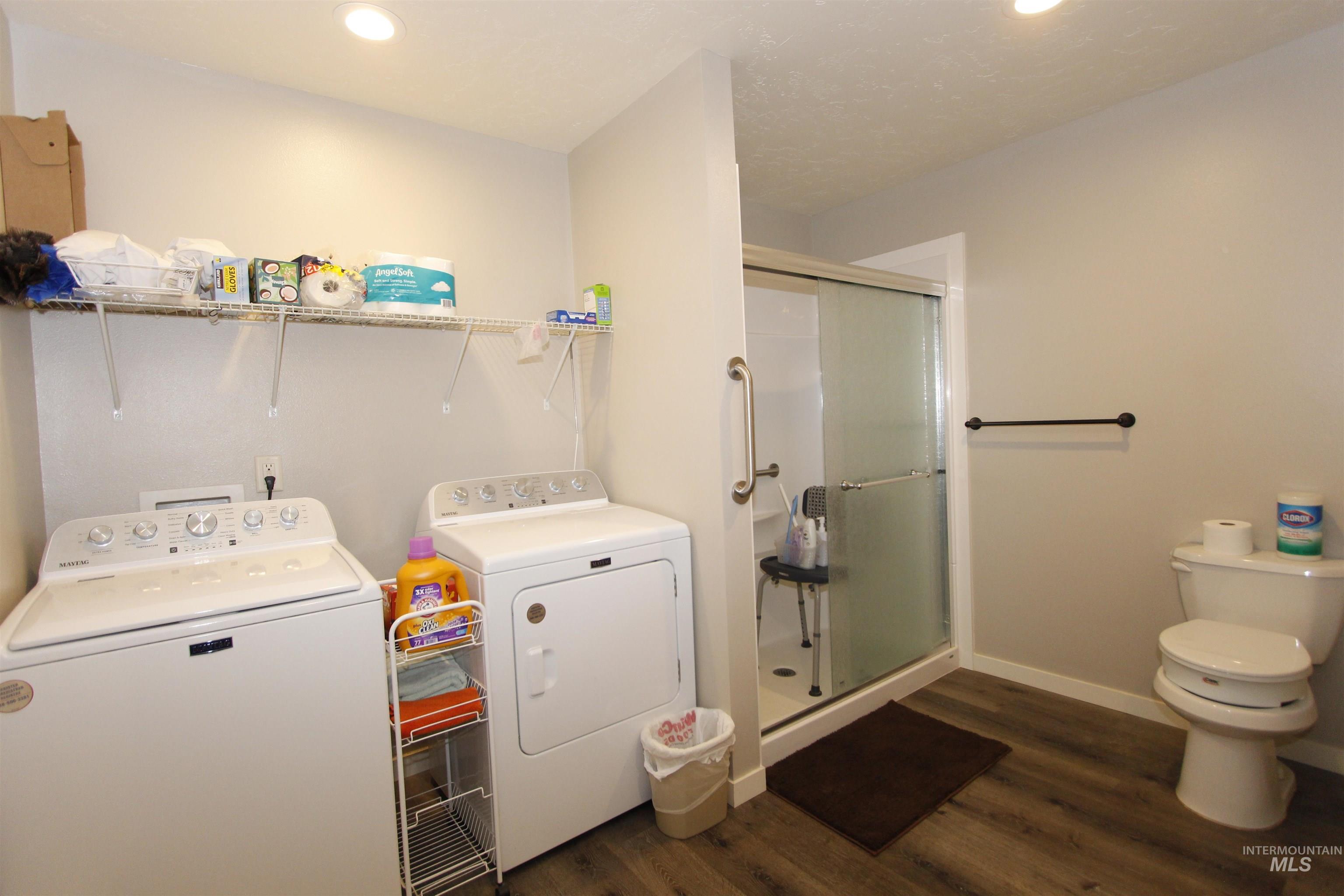 Washroom featuring dark wood finished floors, independent washer and dryer, and recessed lighting