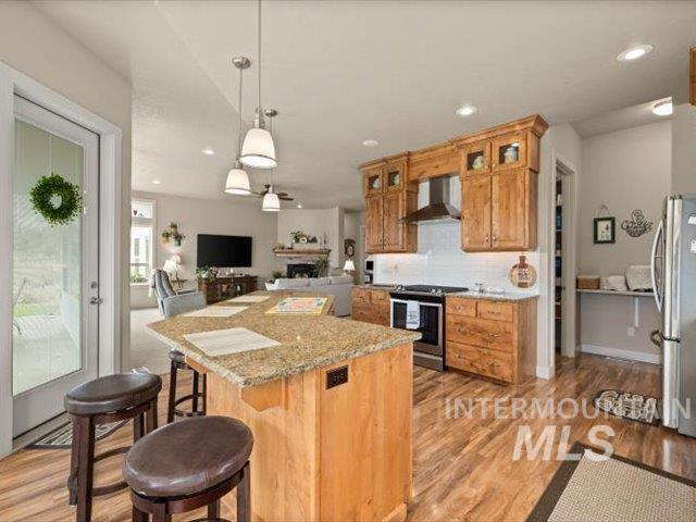 Kitchen with a kitchen breakfast bar, open floor plan, pendant lighting, tasteful backsplash, and light wood-style floors