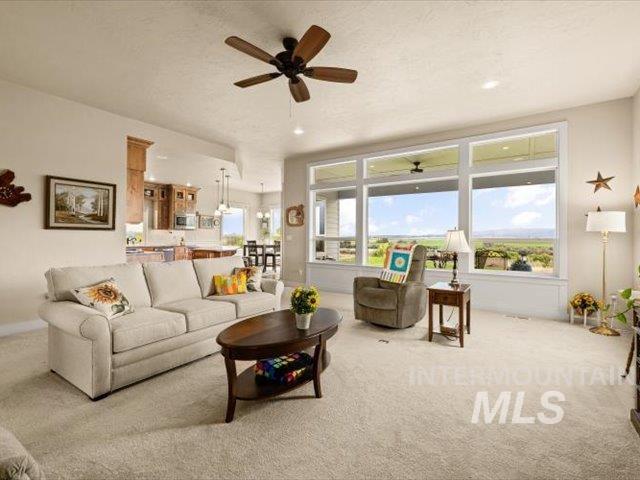 Carpeted living area with healthy amount of natural light and ceiling fan