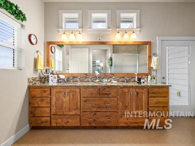 Full bathroom featuring double vanity and baseboards
