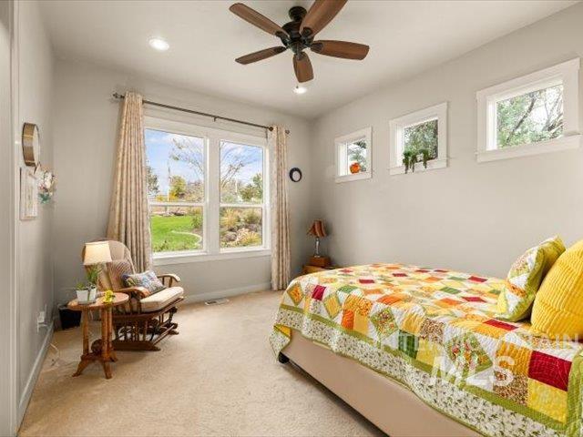 Carpeted bedroom with multiple windows, ceiling fan, and recessed lighting