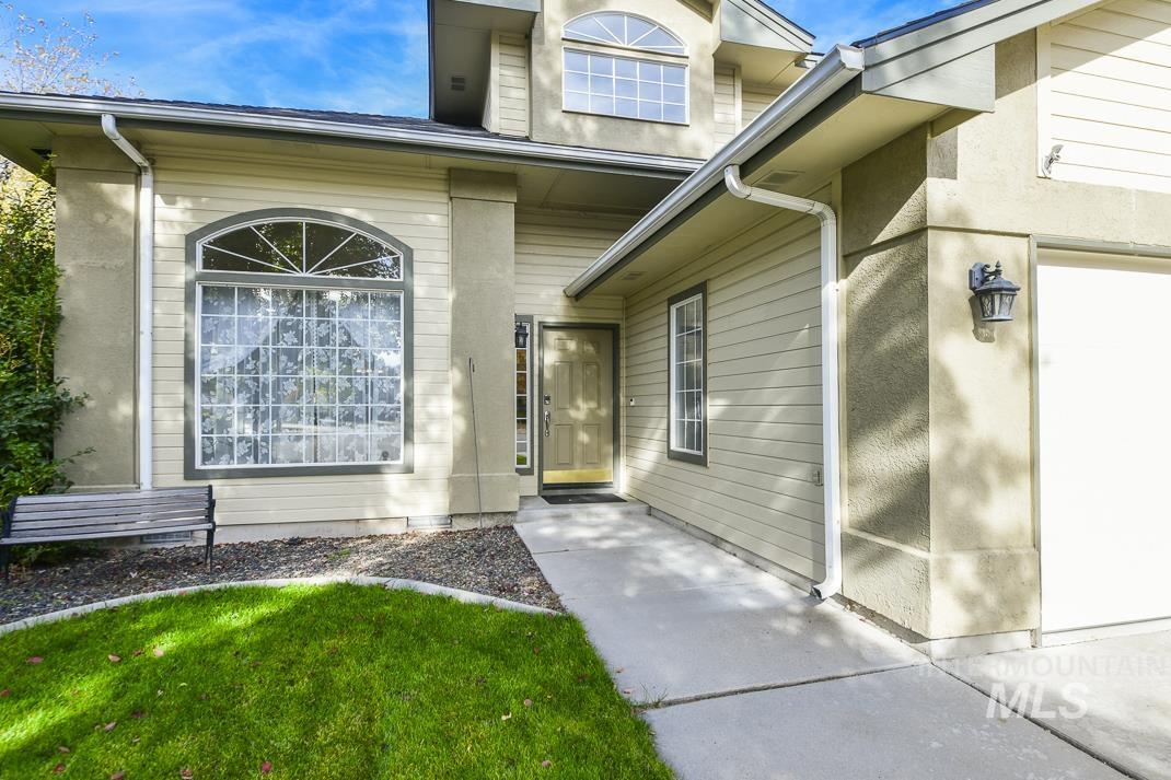 Doorway to property with a garage and a lawn