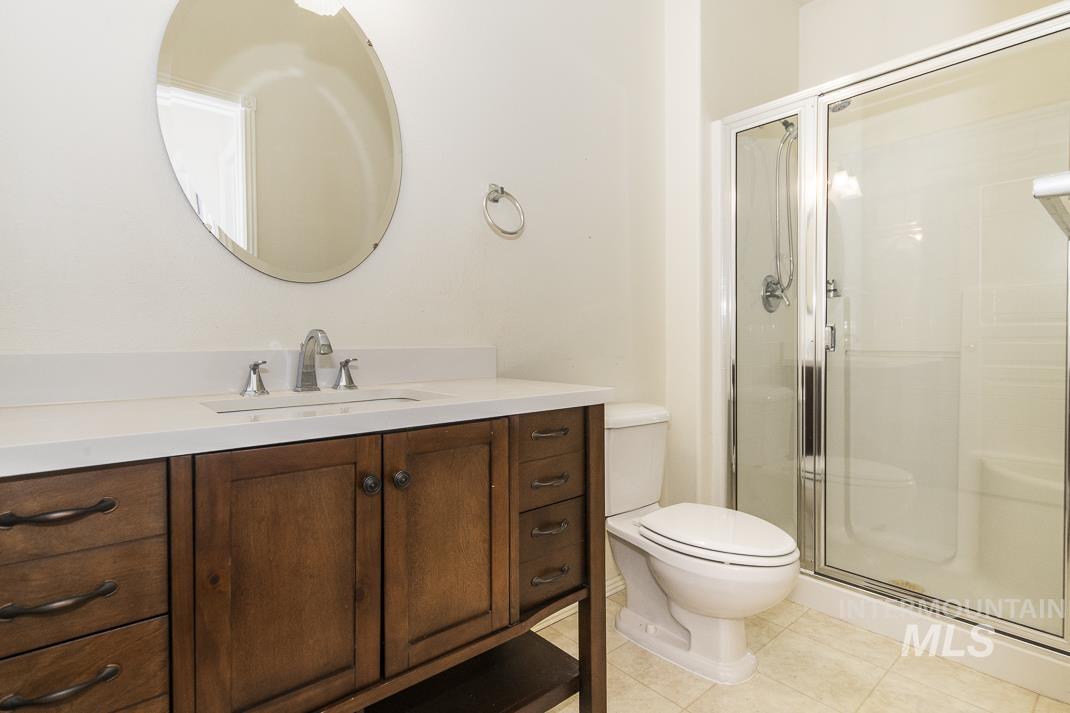 Full bathroom with vanity, light tile patterned flooring, and a stall shower