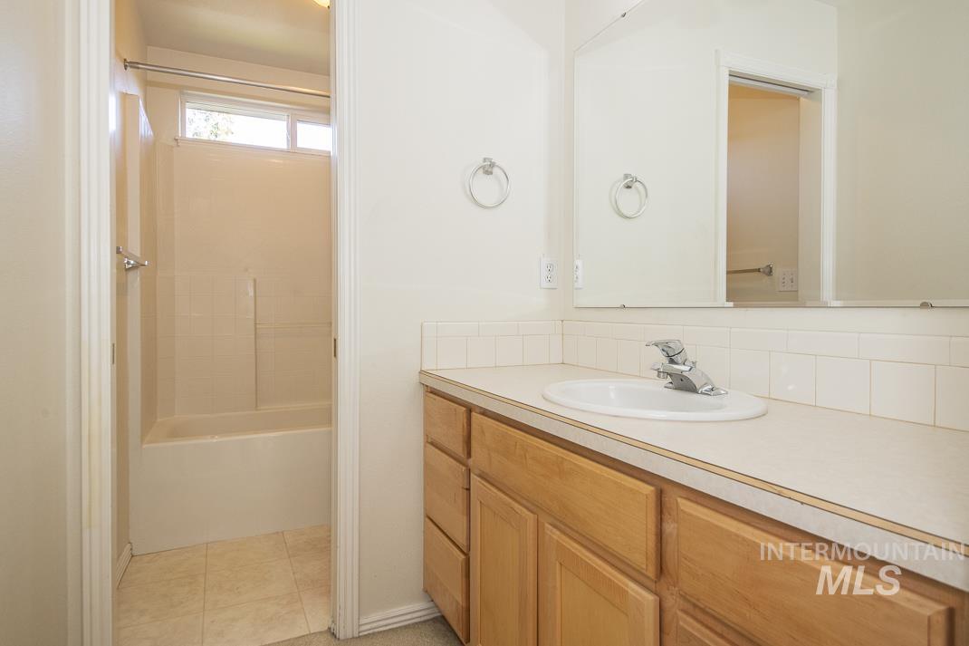 Full bathroom with vanity,  shower combination, light tile patterned floors, and backsplash