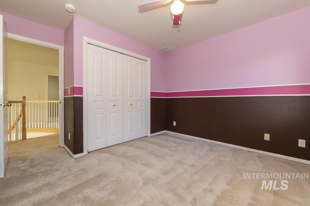 Unfurnished bedroom featuring light carpet, a ceiling fan, and a closet