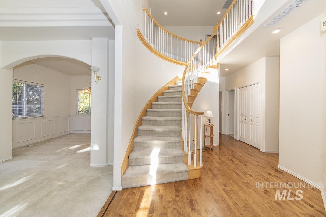 Stairway with arched walkways, wood finished floors, recessed lighting, and a towering ceiling
