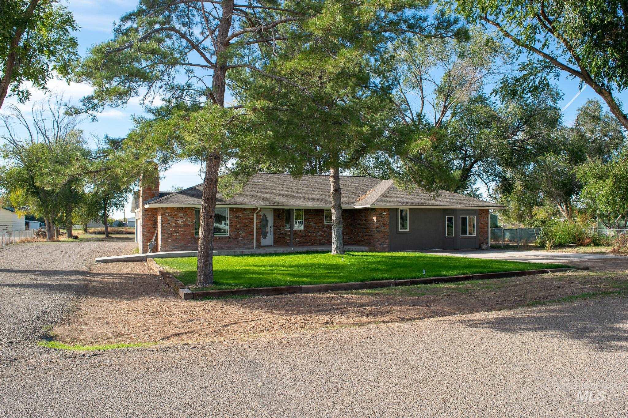 Single story home featuring a front lawn, brick siding, driveway, a chimney, and a shingled roof