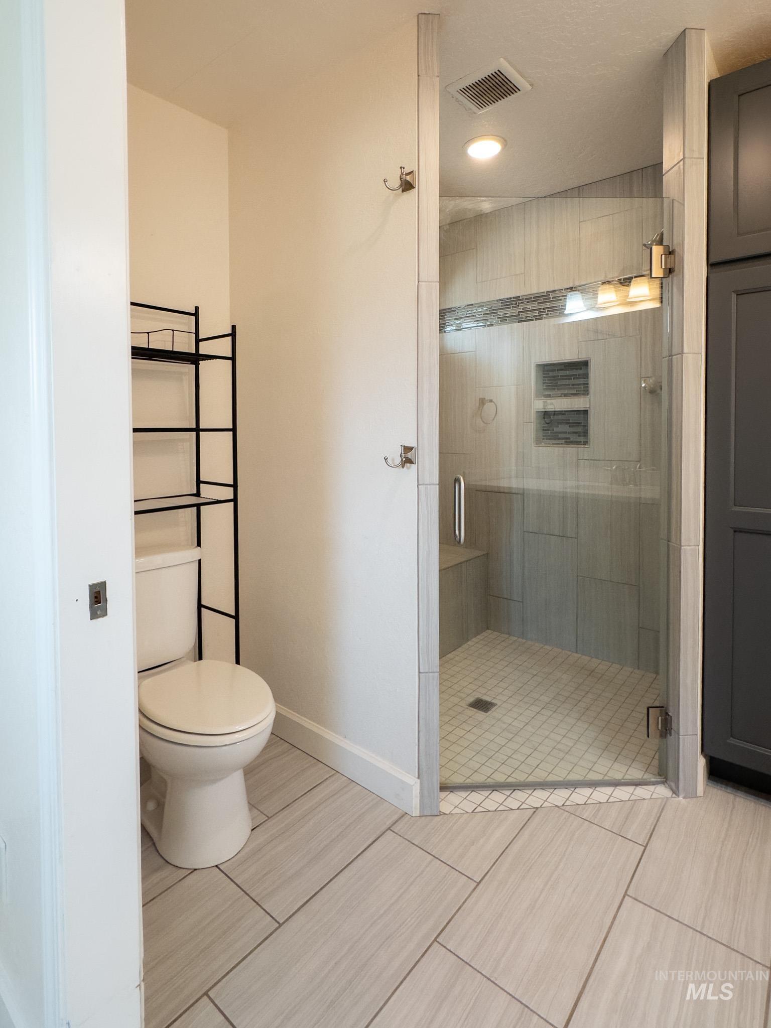 Bathroom with a shower stall and light tile patterned flooring