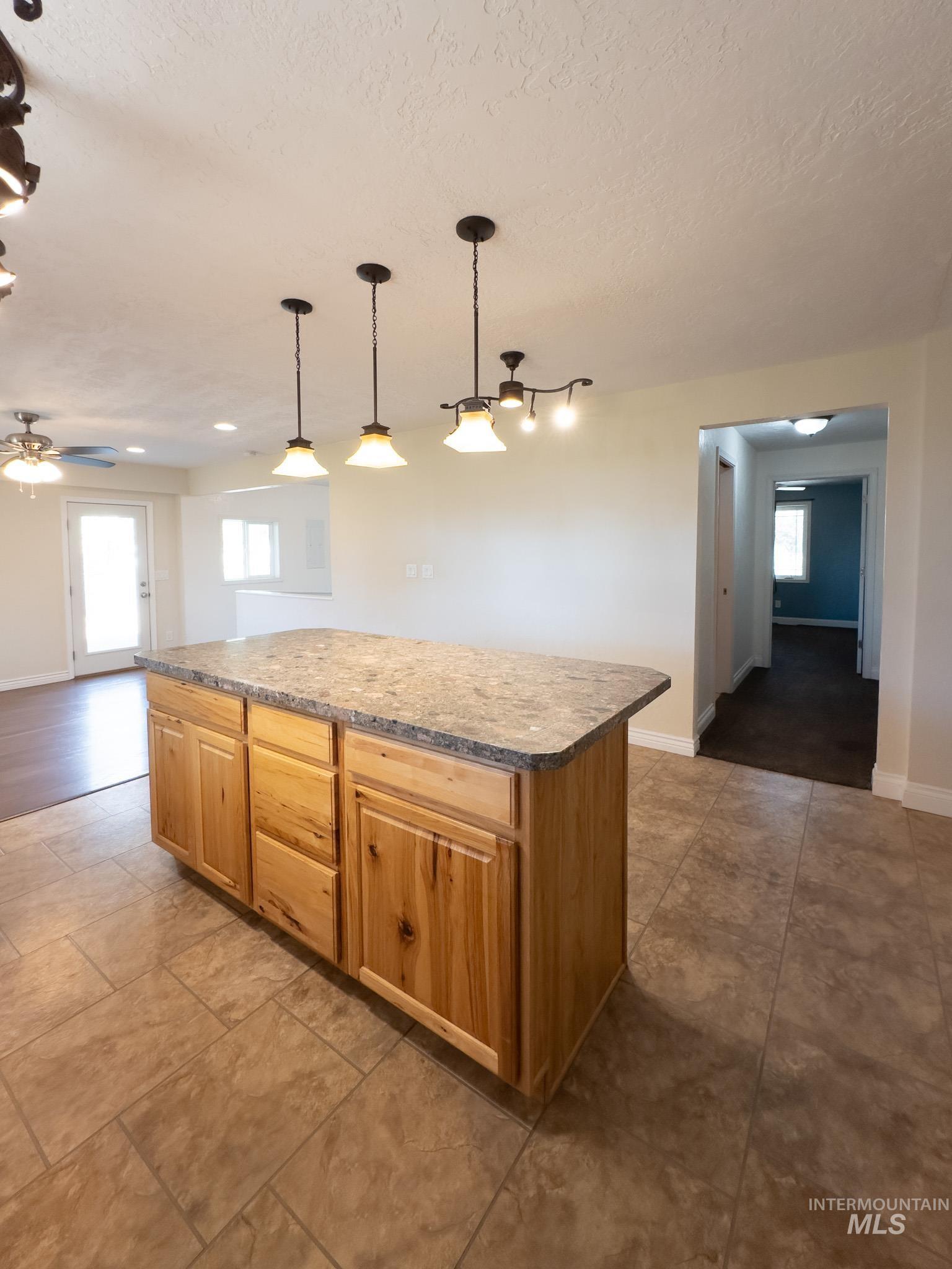 Kitchen with a kitchen island, pendant lighting, a textured ceiling, and open floor plan