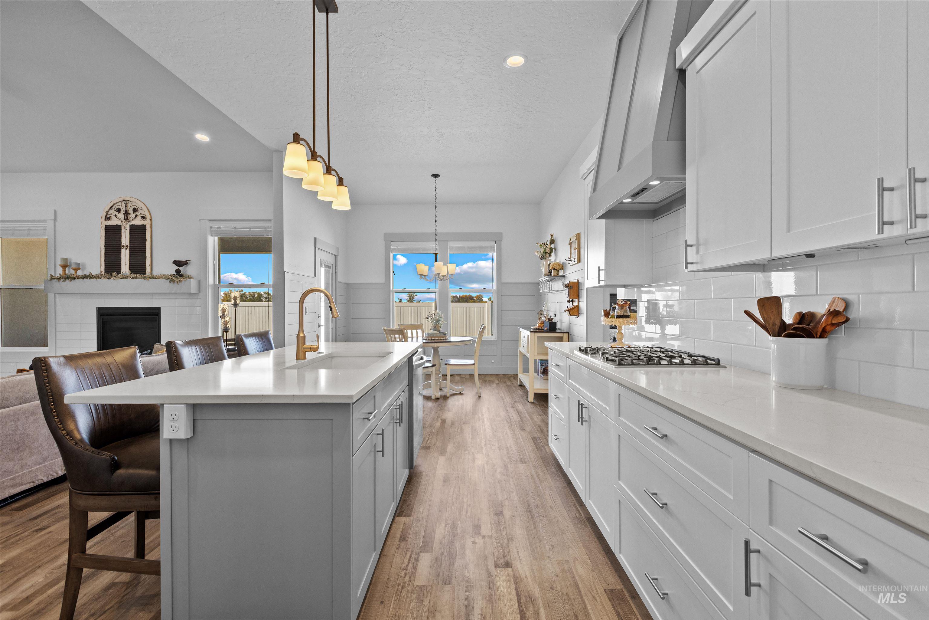 Kitchen featuring a kitchen bar, white cabinets, pendant lighting, light stone counters, and light wood-style flooring