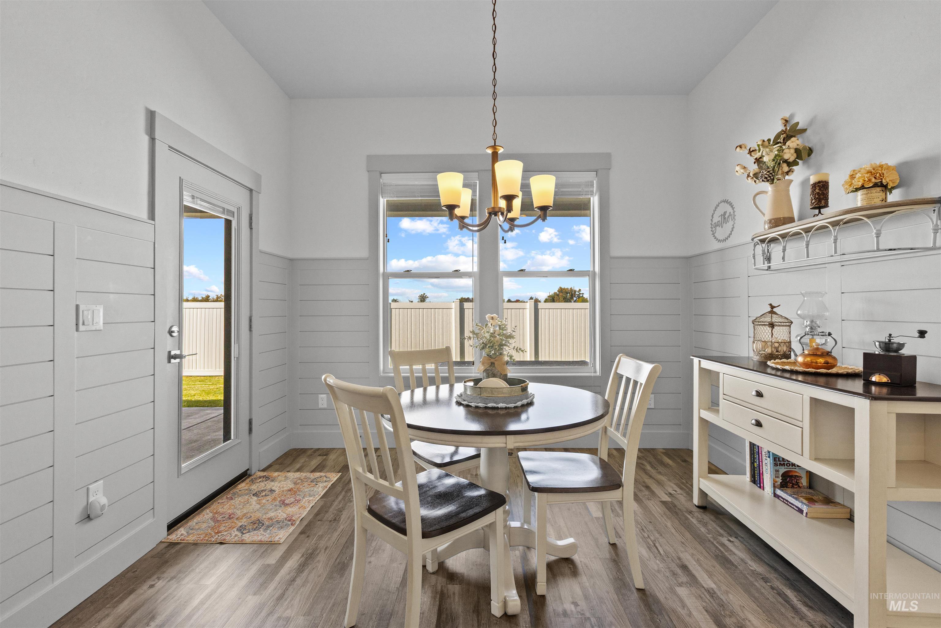 Dining space featuring dark wood-style flooring, wainscoting, and a chandelier