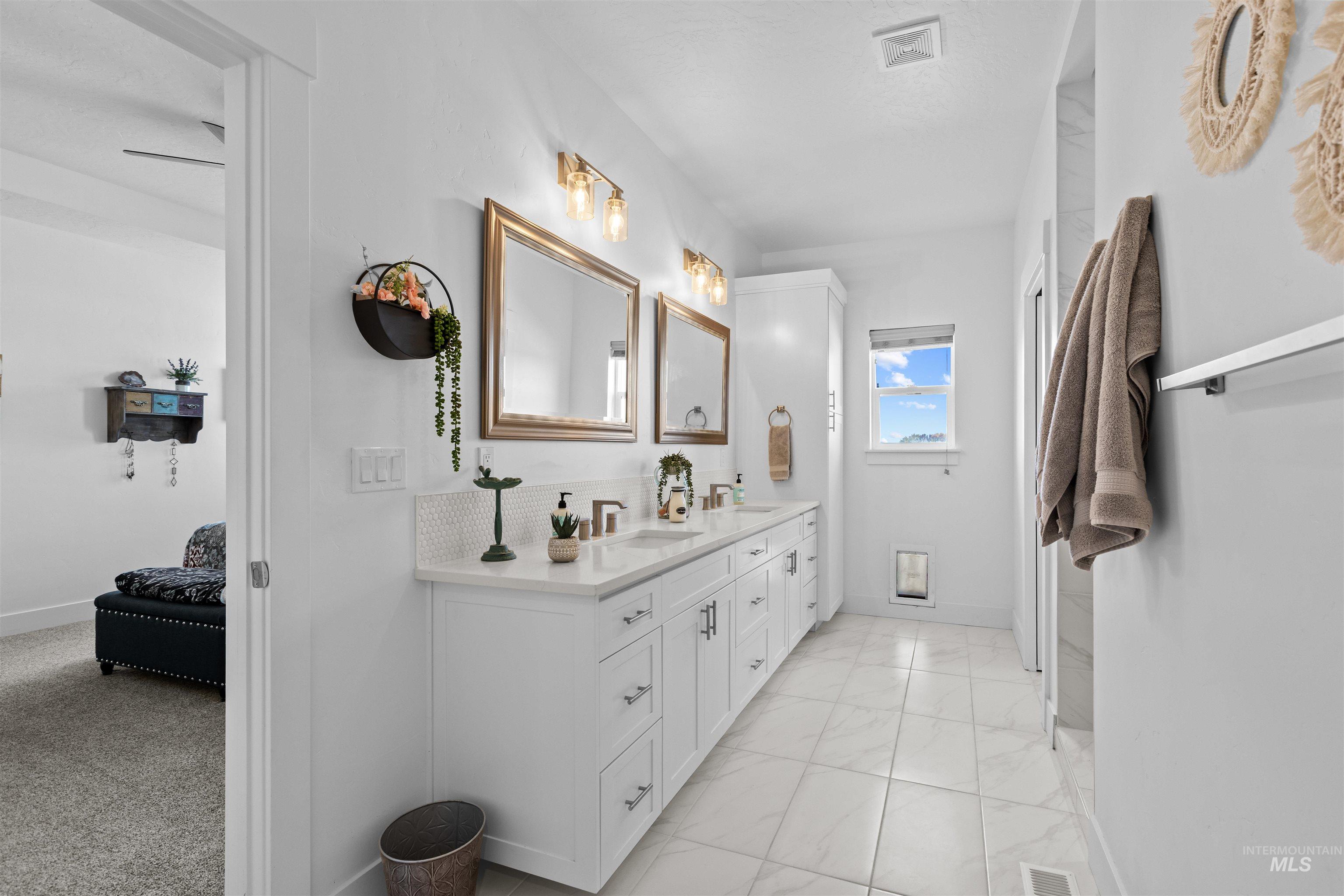 Bathroom featuring double vanity and light marble finish flooring