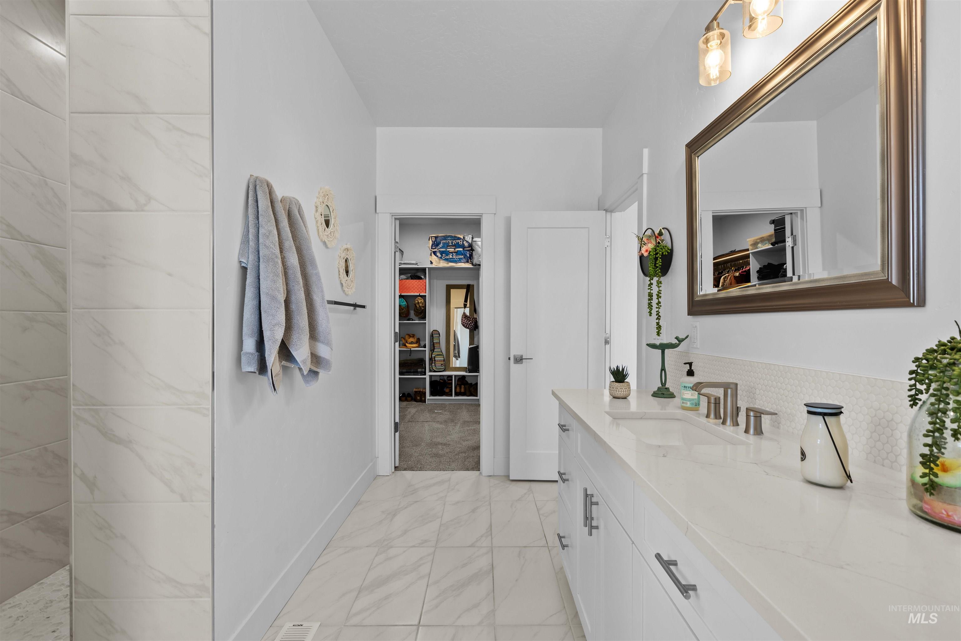 Full bath with a walk in closet, vanity, and light marble finish floors