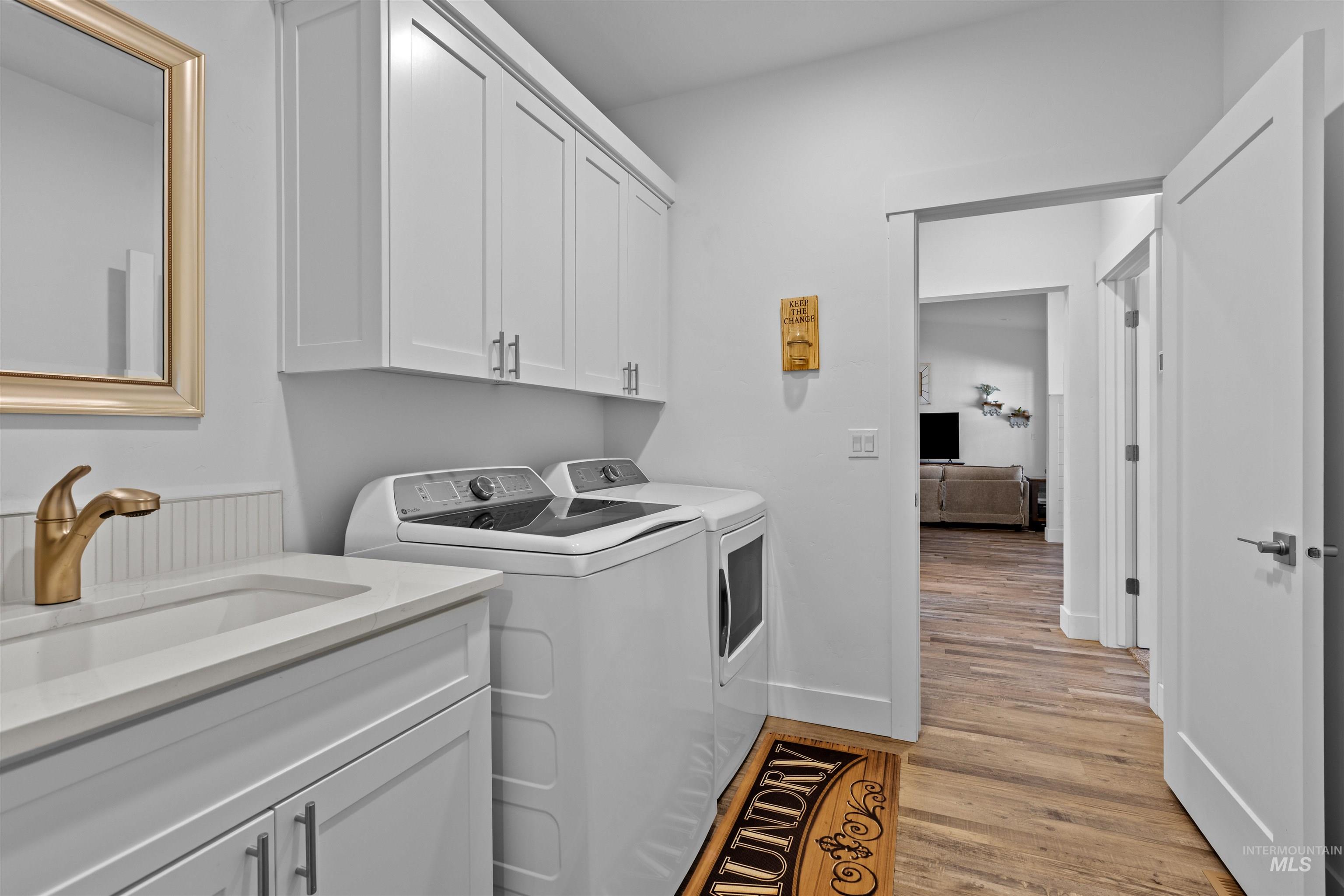 Laundry room with light wood-type flooring, independent washer and dryer, and cabinet space