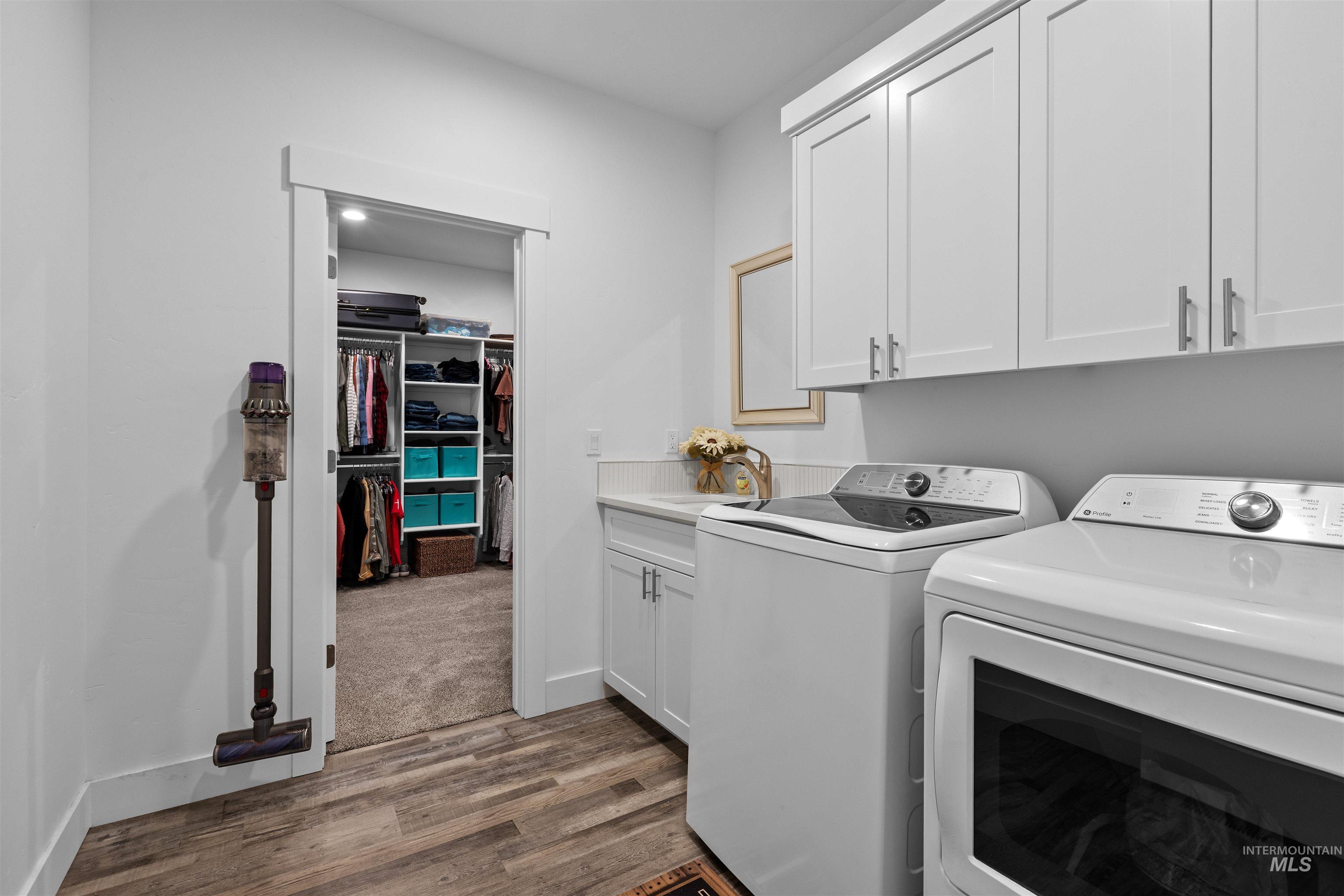 Laundry room with cabinet space, dark wood-style flooring, and washer and clothes dryer