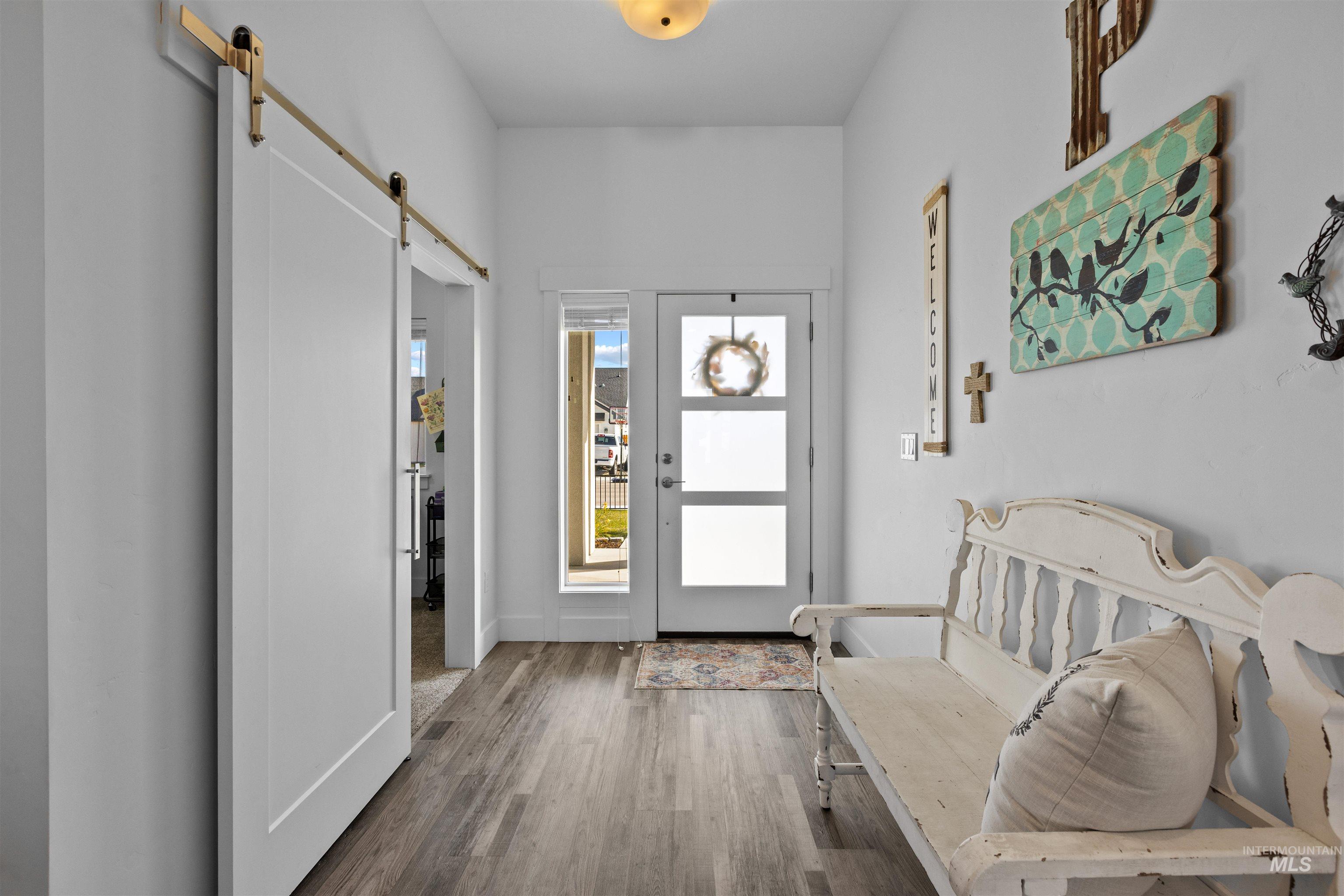 Foyer with a barn door and wood finished floors