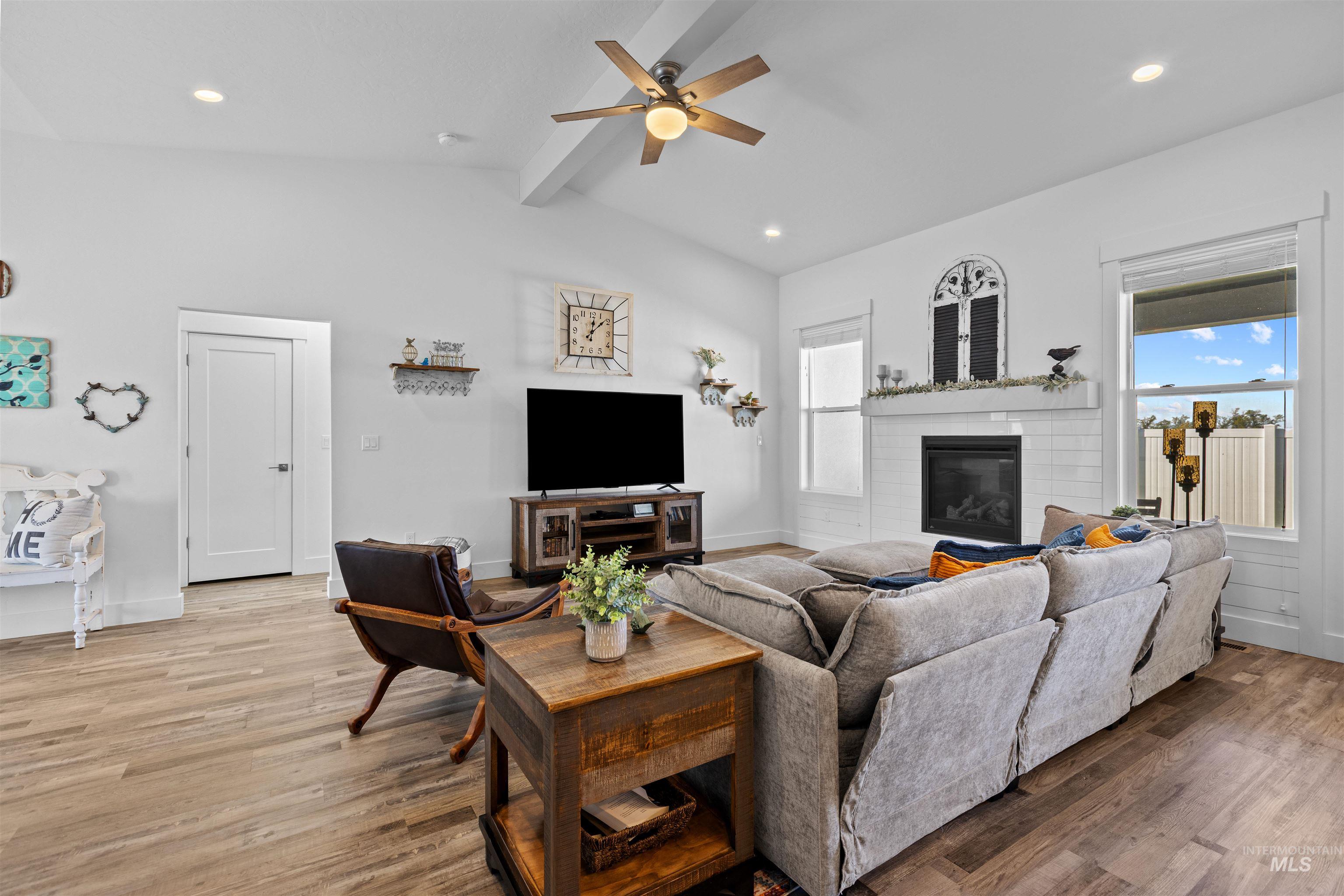 Living area with light wood finished floors, a glass covered fireplace, recessed lighting, and ceiling fan