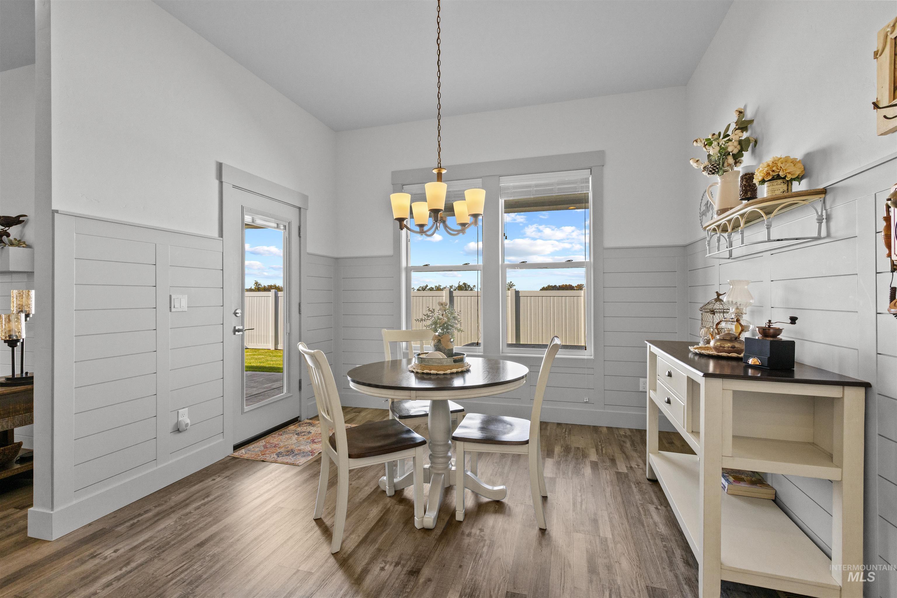 Dining room with dark wood finished floors, a wainscoted wall, and a chandelier