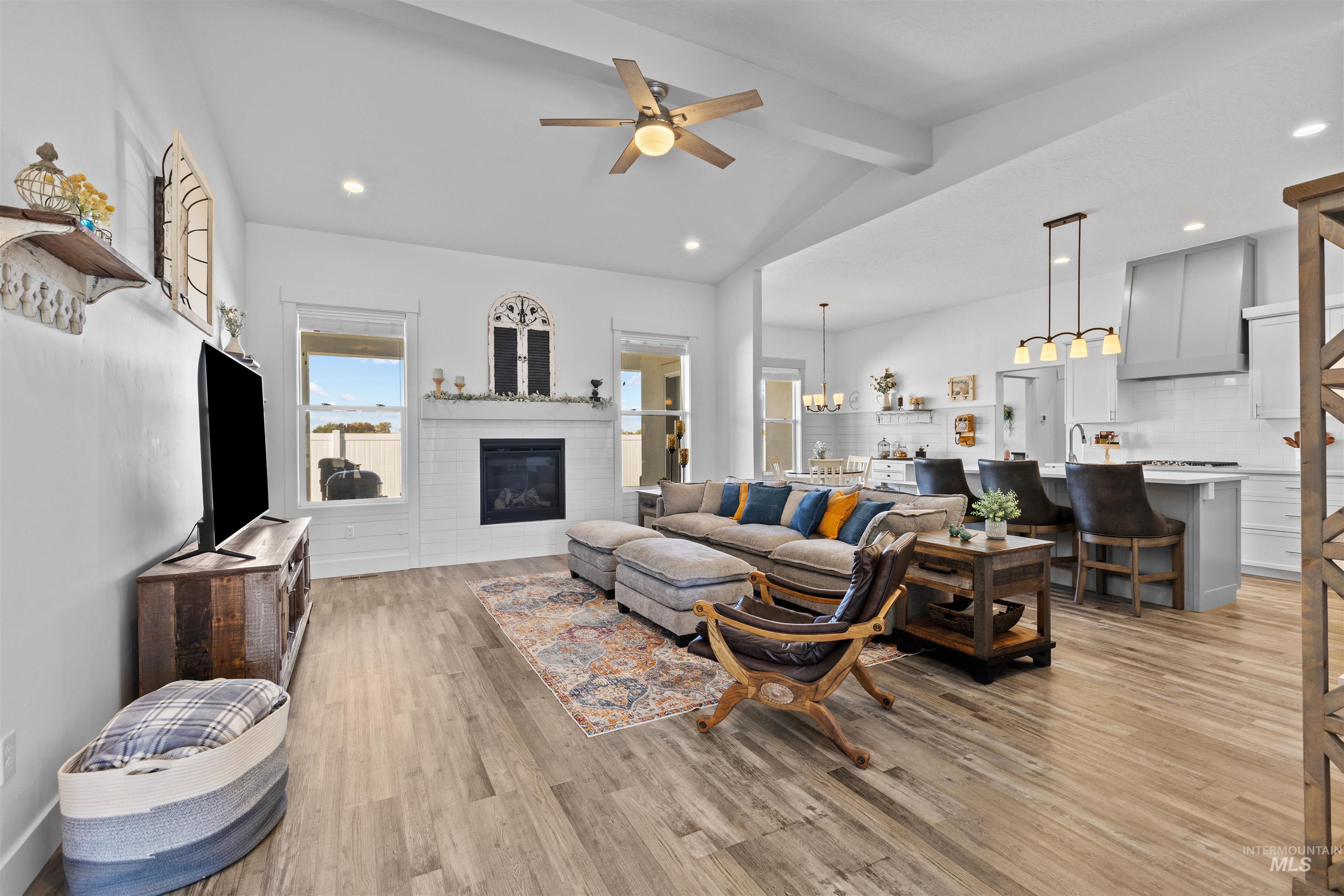 Living room featuring recessed lighting, ceiling fan, light wood-style flooring, a glass covered fireplace, and a chandelier