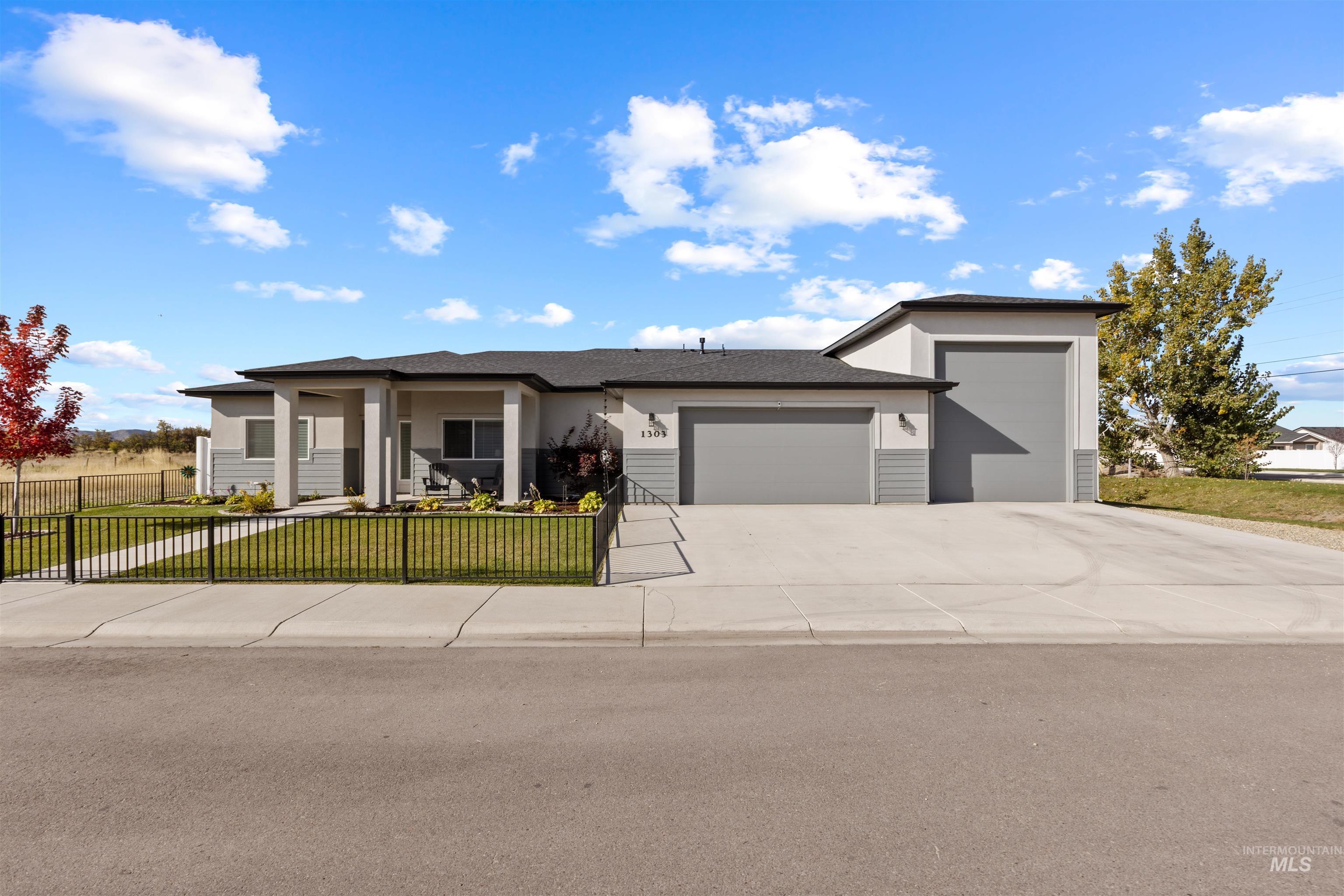 View of front of house with an attached garage, driveway, a fenced front yard, stucco siding, and a porch