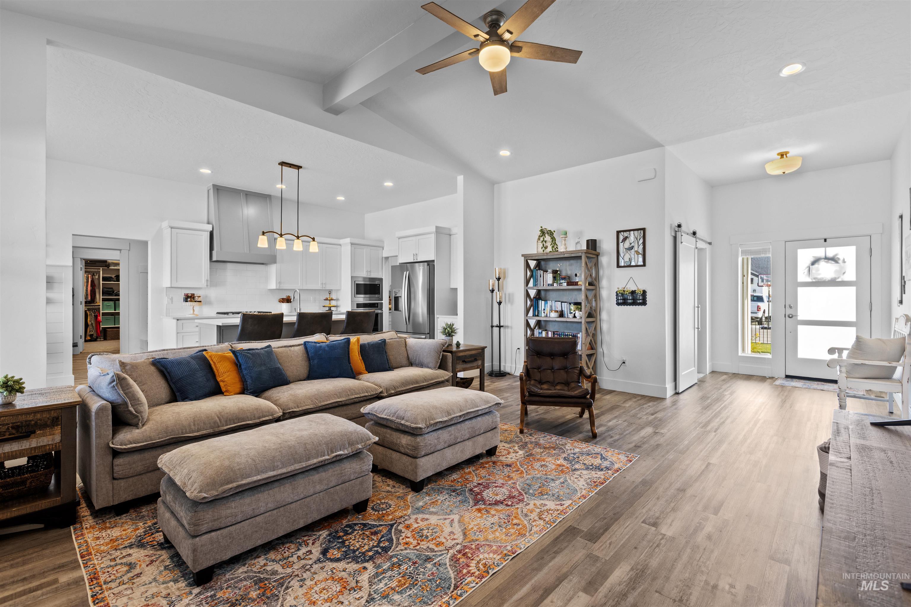 Living room featuring a barn door, dark wood-style floors, recessed lighting, and ceiling fan